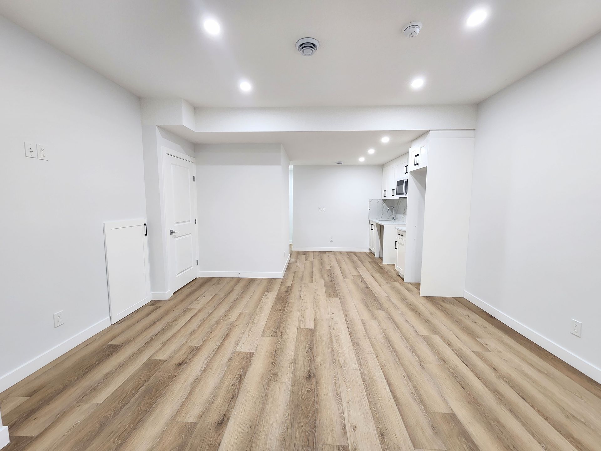 Modern empty room with Vinyl wood flooring and recessed lighting in a Calgary, Alberta home.