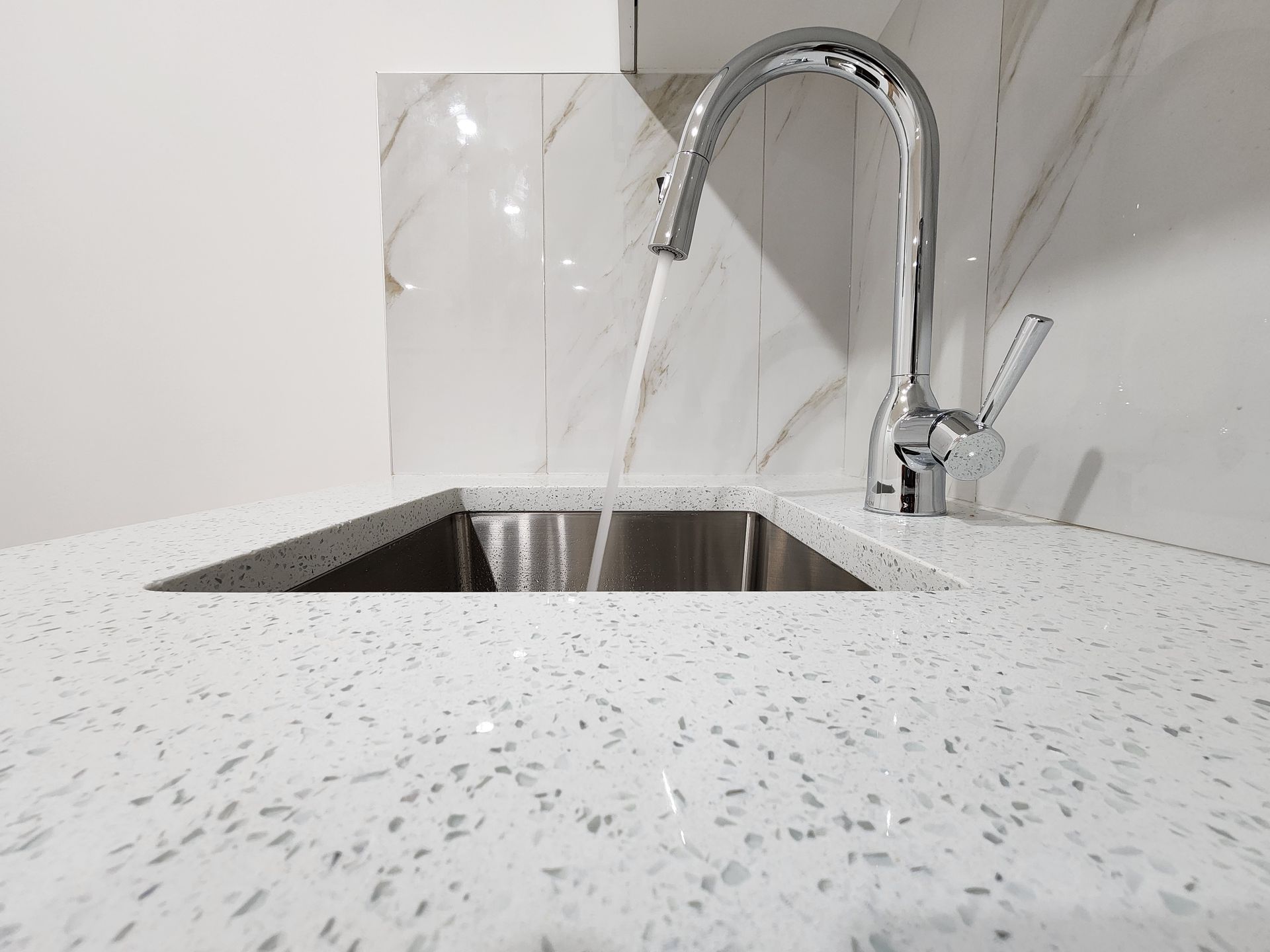 Close-up of a stainless steel kitchen sink with a high arc faucet and Quartz countertop in Calgary