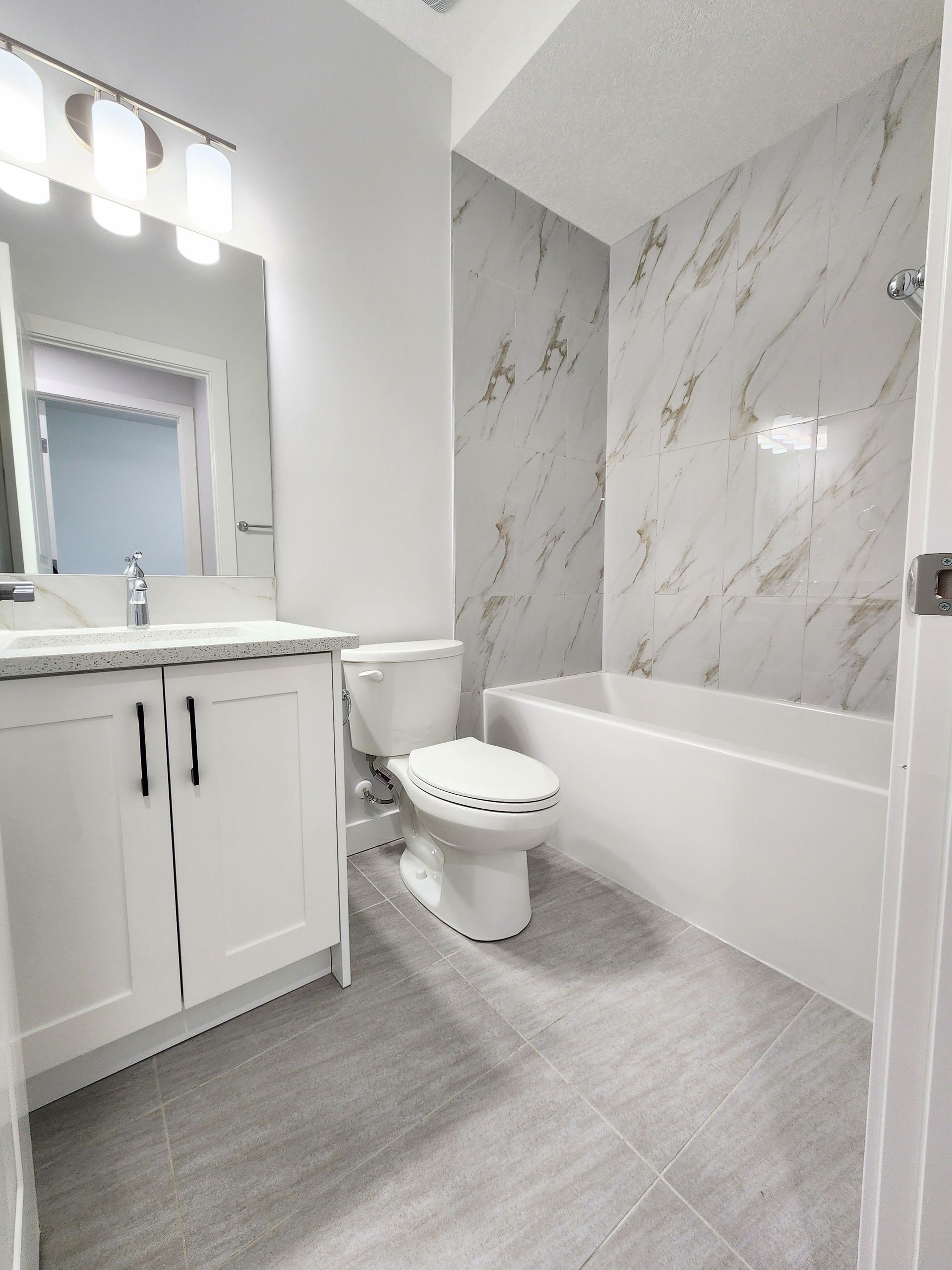 images shows a white bathroom with marble tiles and modern fixtures 