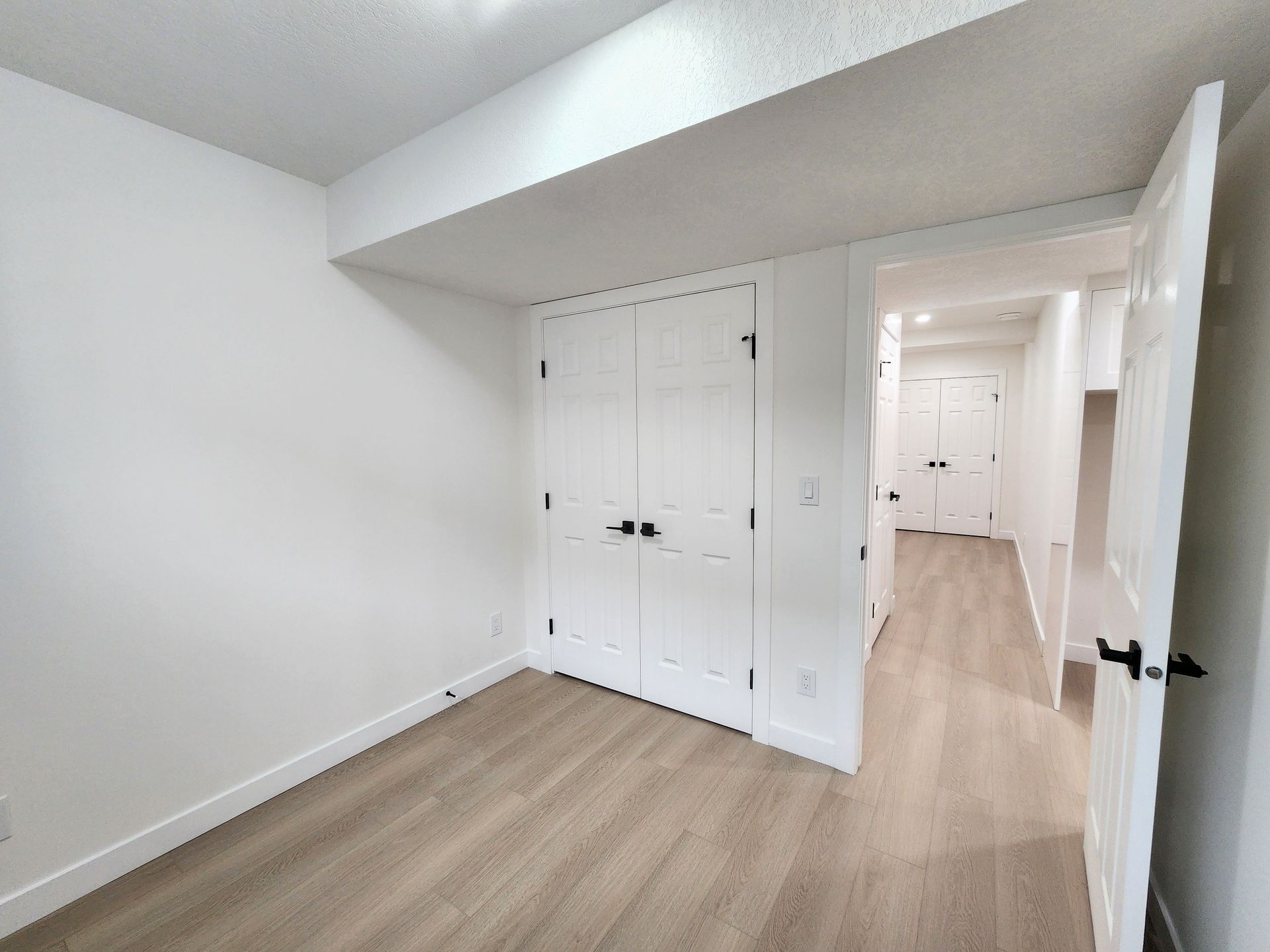 Pictures shows a bedroom with a closet finished with Luxury Vinyl Plank in a basement renovation in Calgary