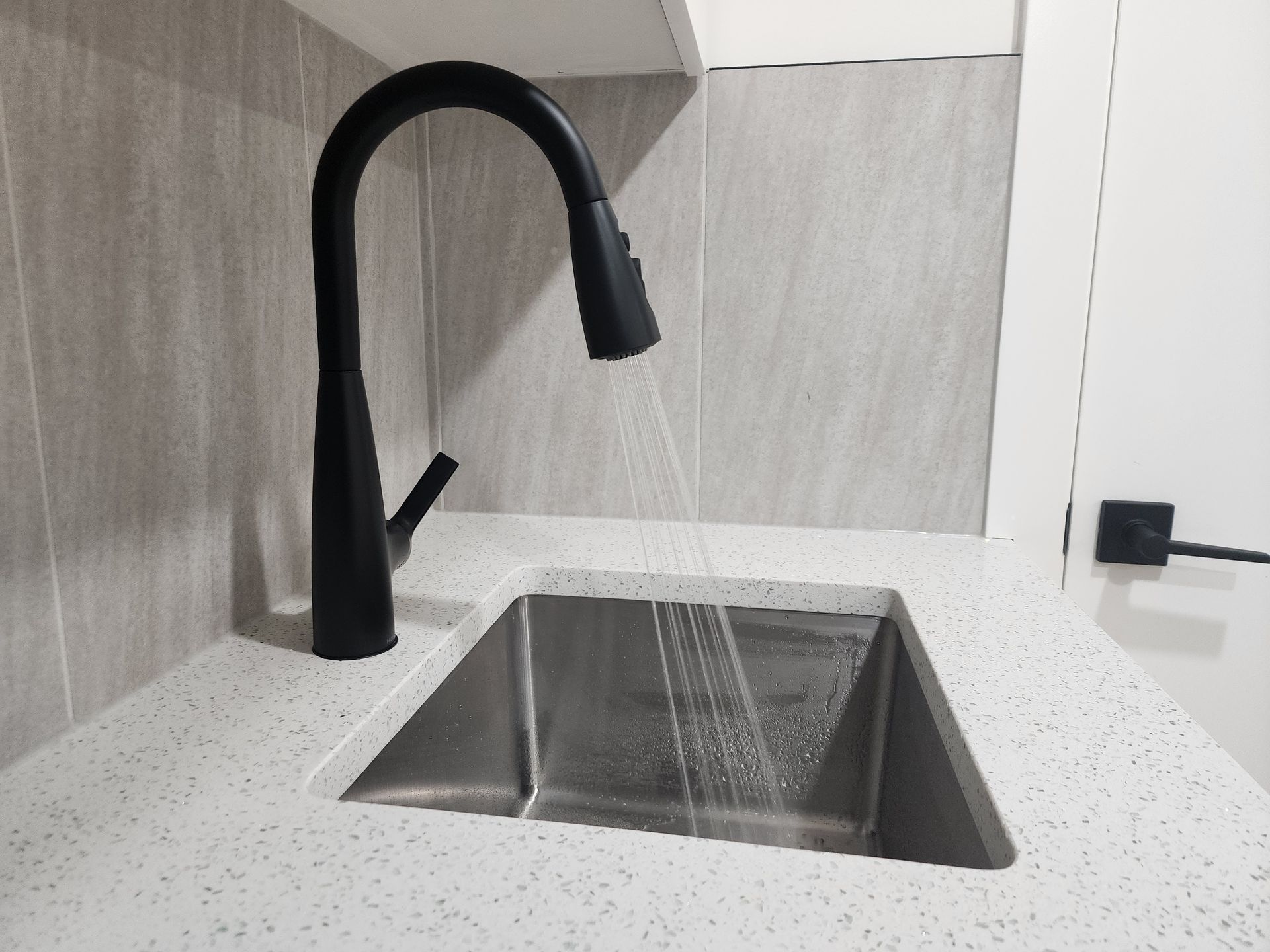 A quality black pull-down Moen kitchen faucet and a sparkle infused quartz countertop