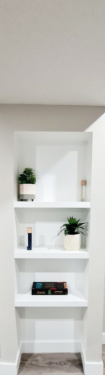images shows 3 painted grade white MDF wood shelves with a book, flower Vas placed on each shelf