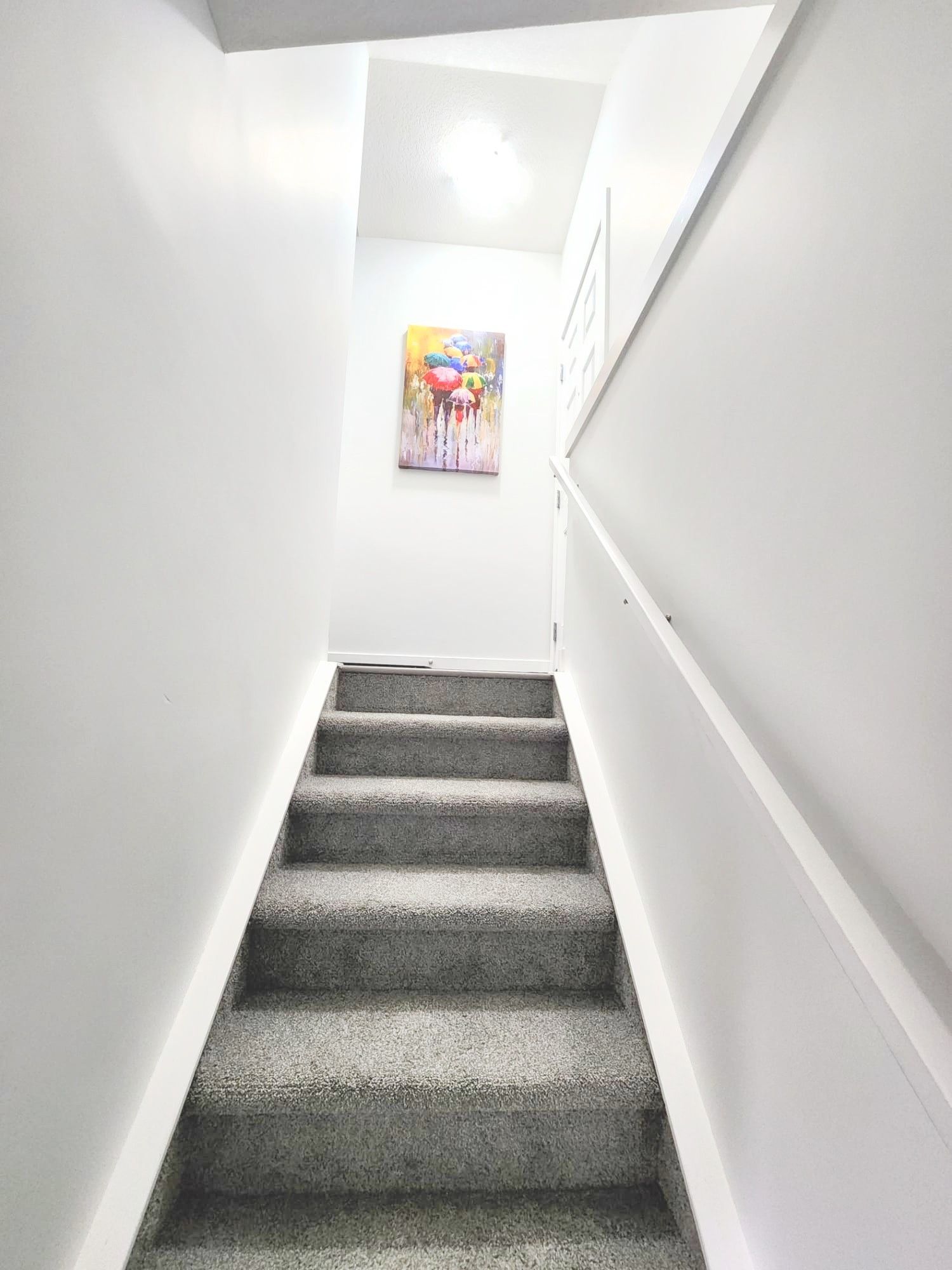 This pictures shows a painting on a wall when looking up the stairs in a basement suite in Calgary, Alberta