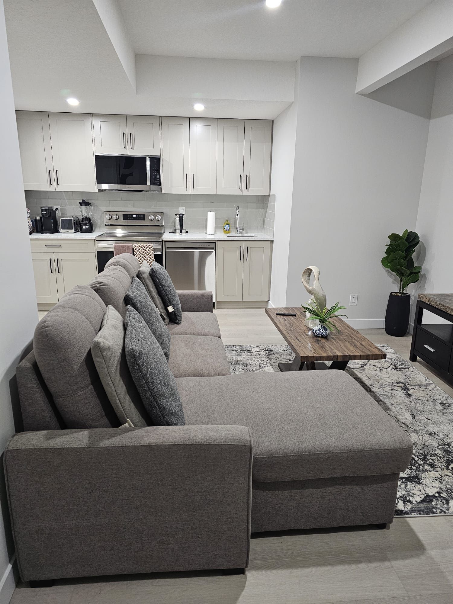 A spacious living area with lots of natural light from both the window and the door lit with a warn Vinyl flooring  