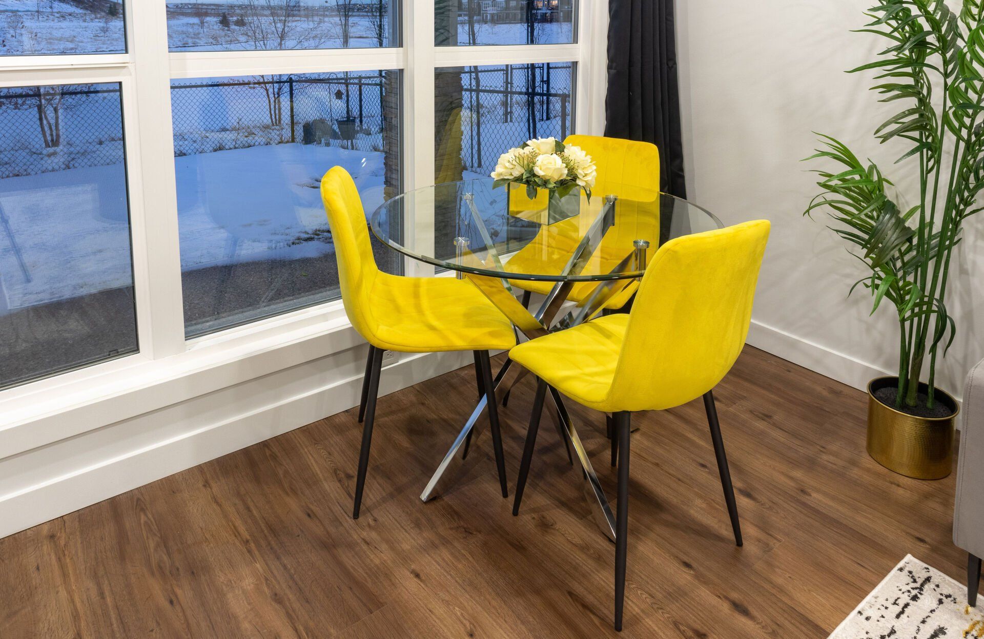 image of a round glass dinning table with three yellow chairs in basement suite