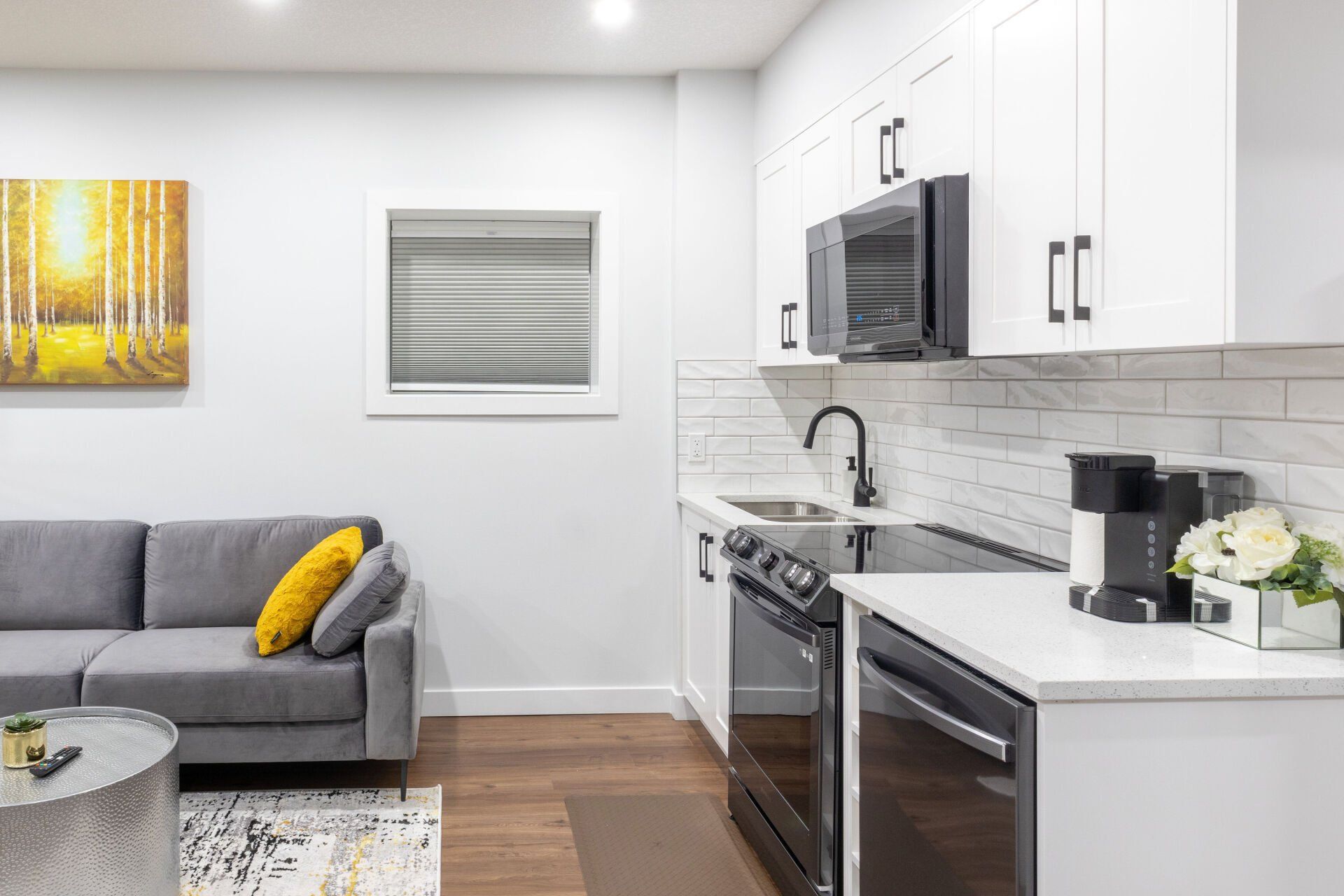 A modern kitchenette with black appliances, chic decor and a window  in a well light space 