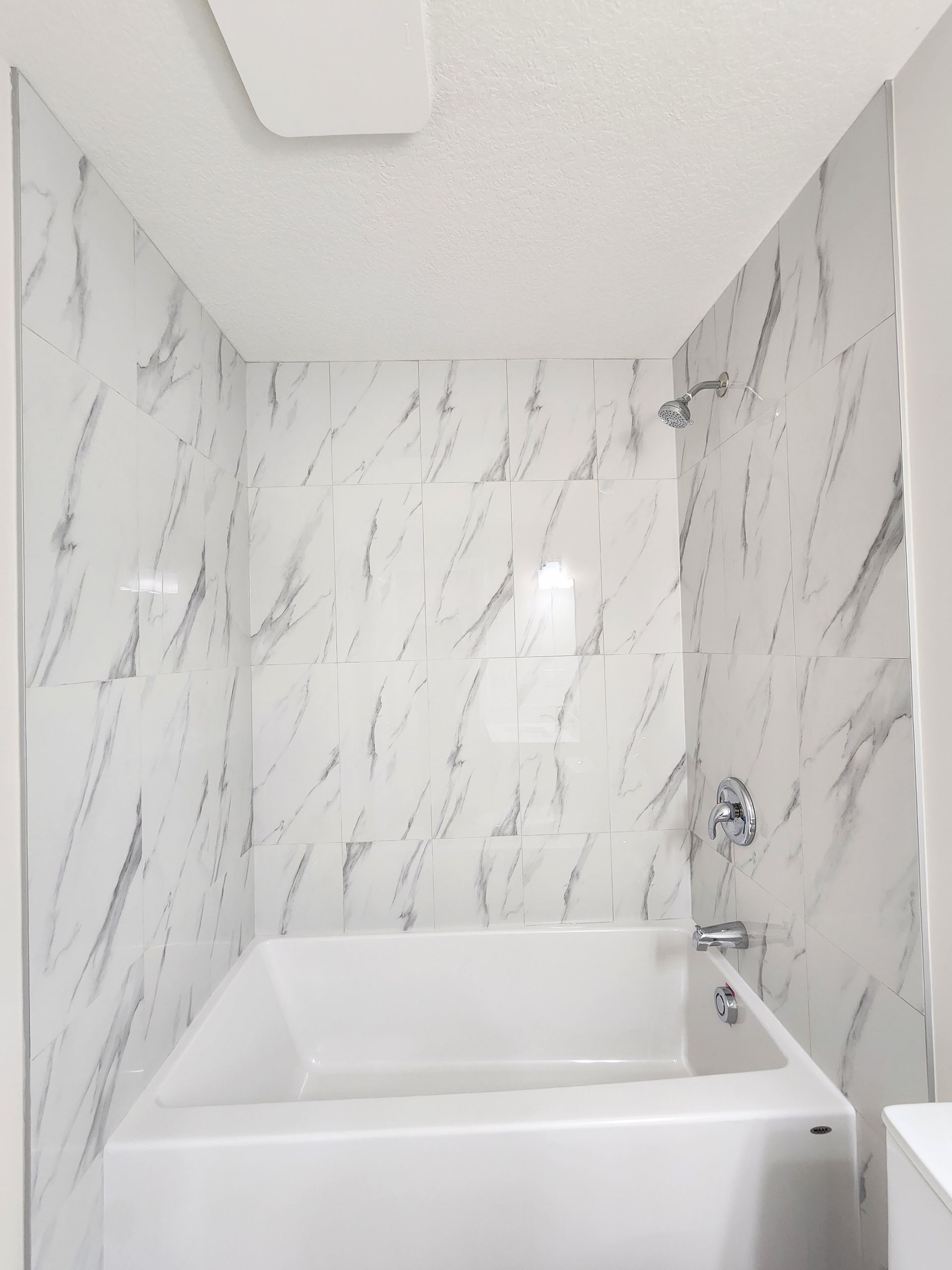 Close up picture of a bathroom showing white Spec porcelain tiles, chrome hardware within a basement development project