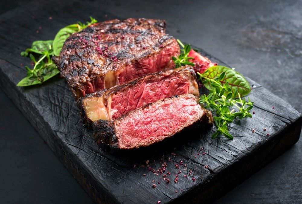 Medium Rare Steak on A Weathered Black Wooden Board — Romanas Italian Restaurant in Nobby Beach, QLD