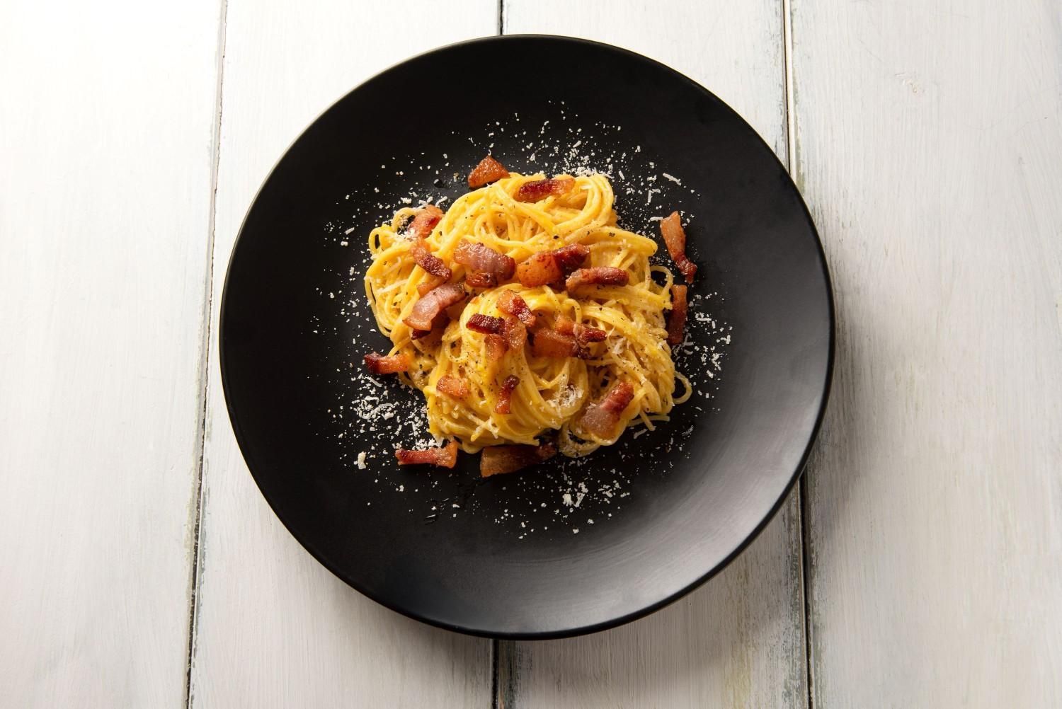 Spaghetti Carbonara on A Black Plate — Romanas Italian Restaurant in Nobby Beach, QLD