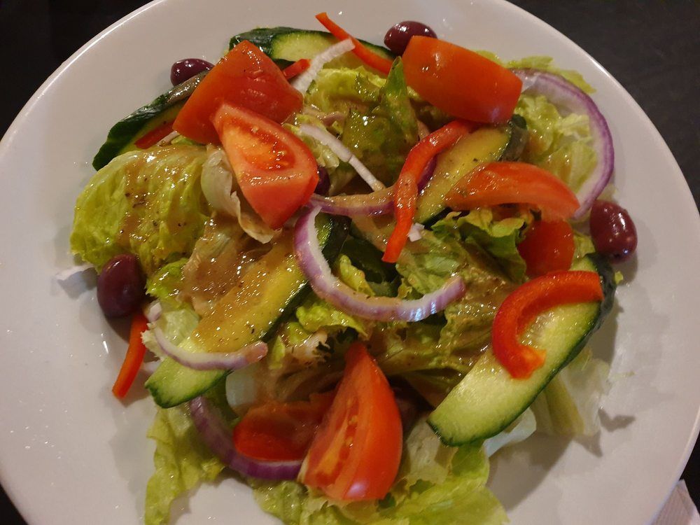 A group of people are sitting at a table eating food and drinking wine — Romanas Italian Restaurant in Nobby Beach, QLD