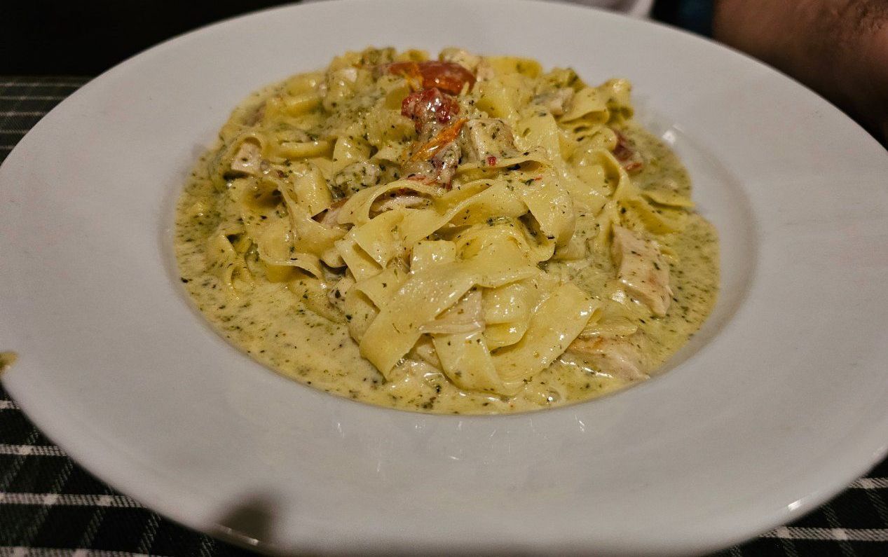 A White Plate Topped With Pasta and Sauce on a Table — Romanas Italian Restaurant in Nobby Beach, QLD