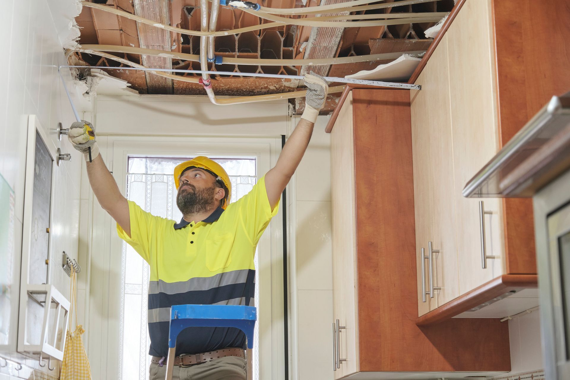 Construction worker inspecting damaged kitchen ceiling.