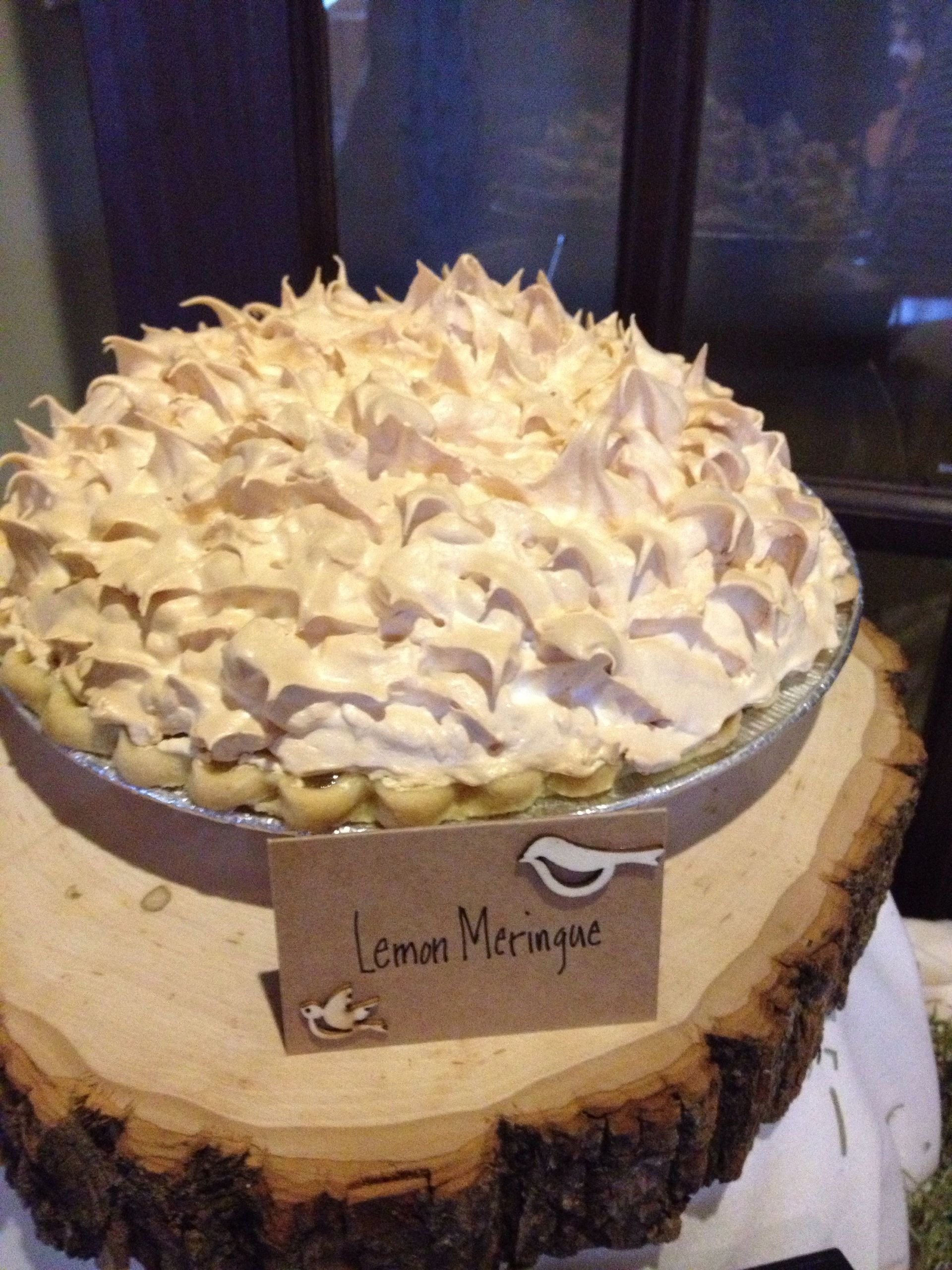 a lemon meringue pie is sitting on a piece of wood