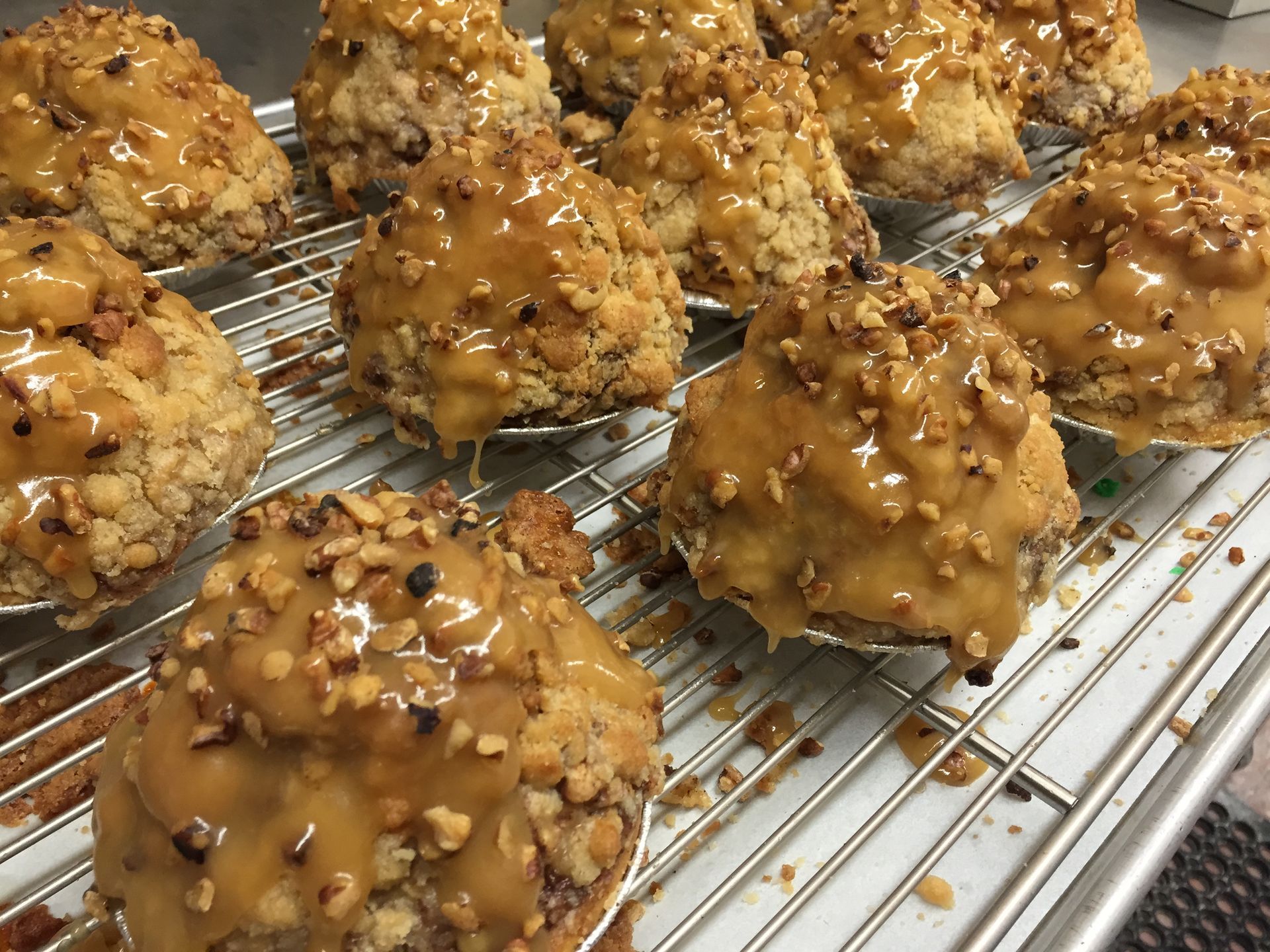 a bunch of muffins covered in caramel and nuts are sitting on a cooling rack .