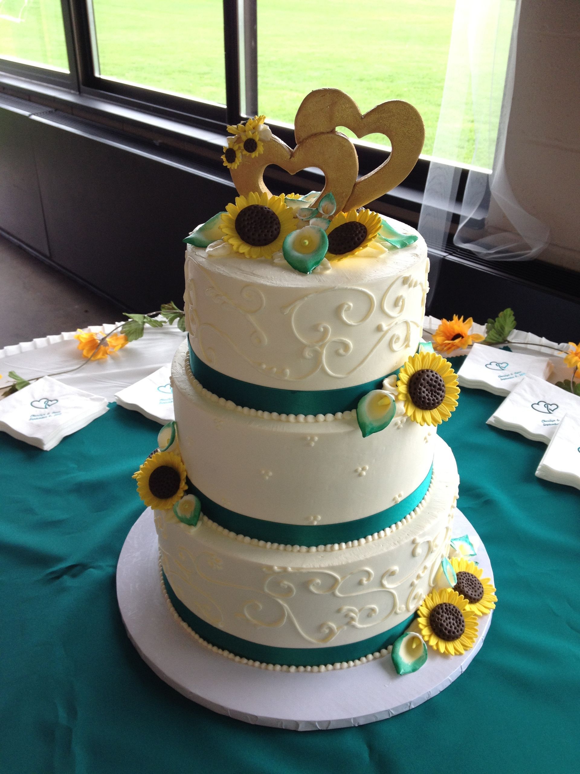 a wedding cake with sunflowers and a heart on top