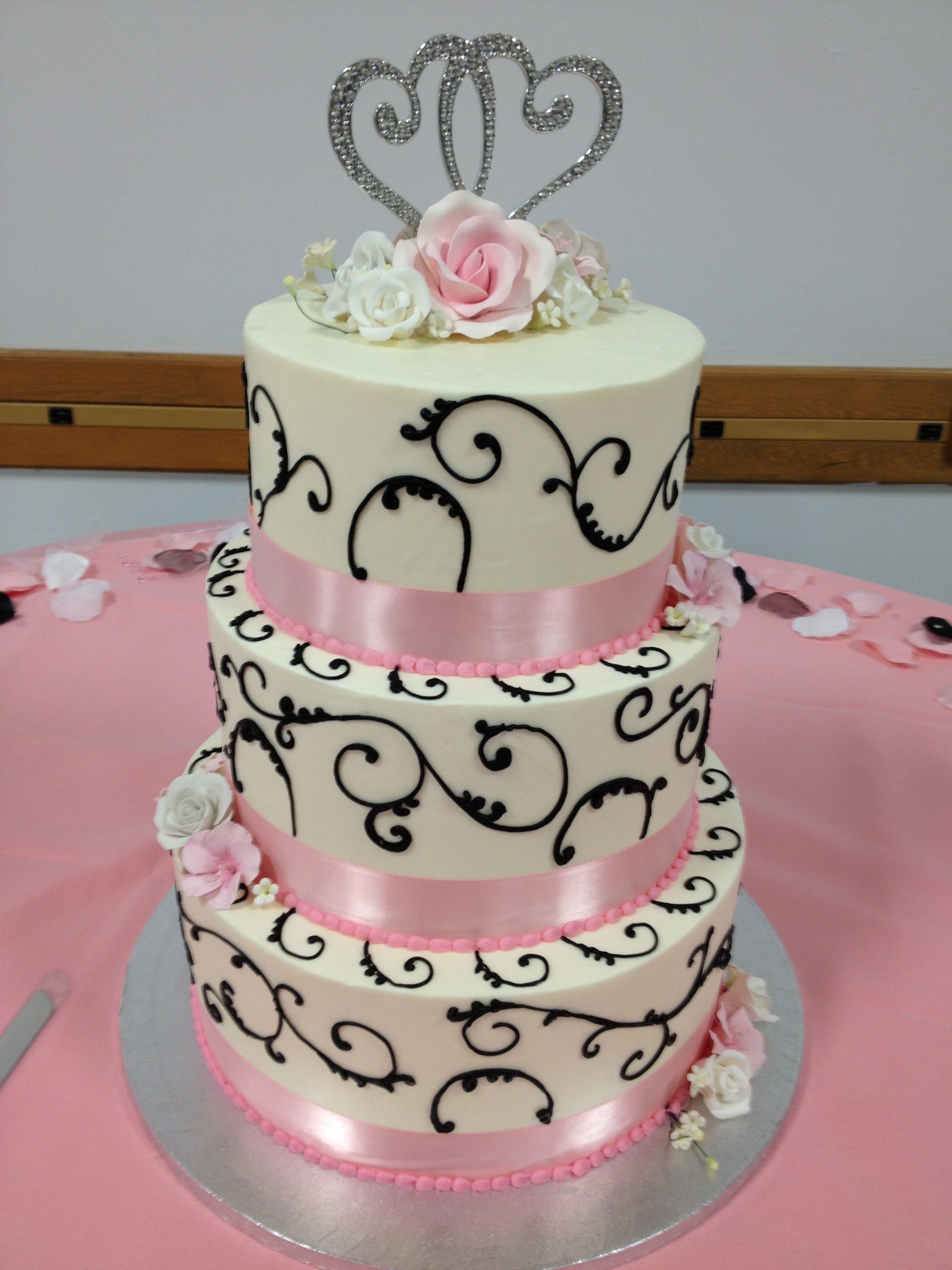 a white cake with black swirls and a pink ribbon