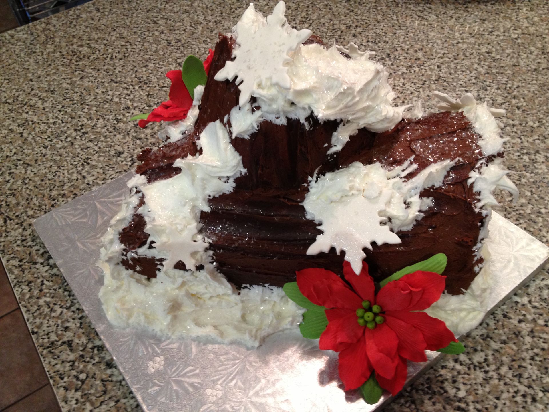 a chocolate cake with white frosting and red flowers on top