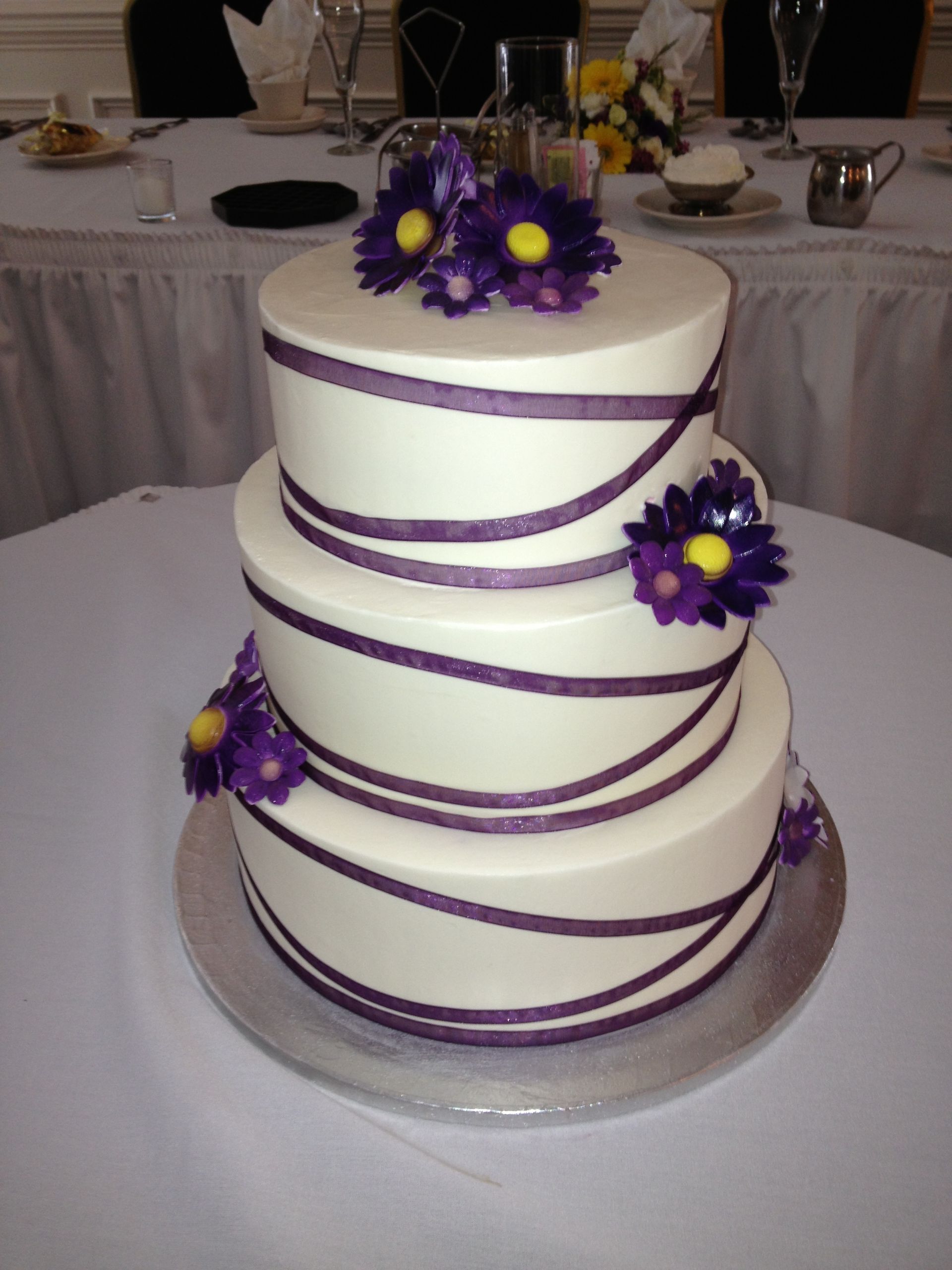 a white cake with purple and yellow flowers on top