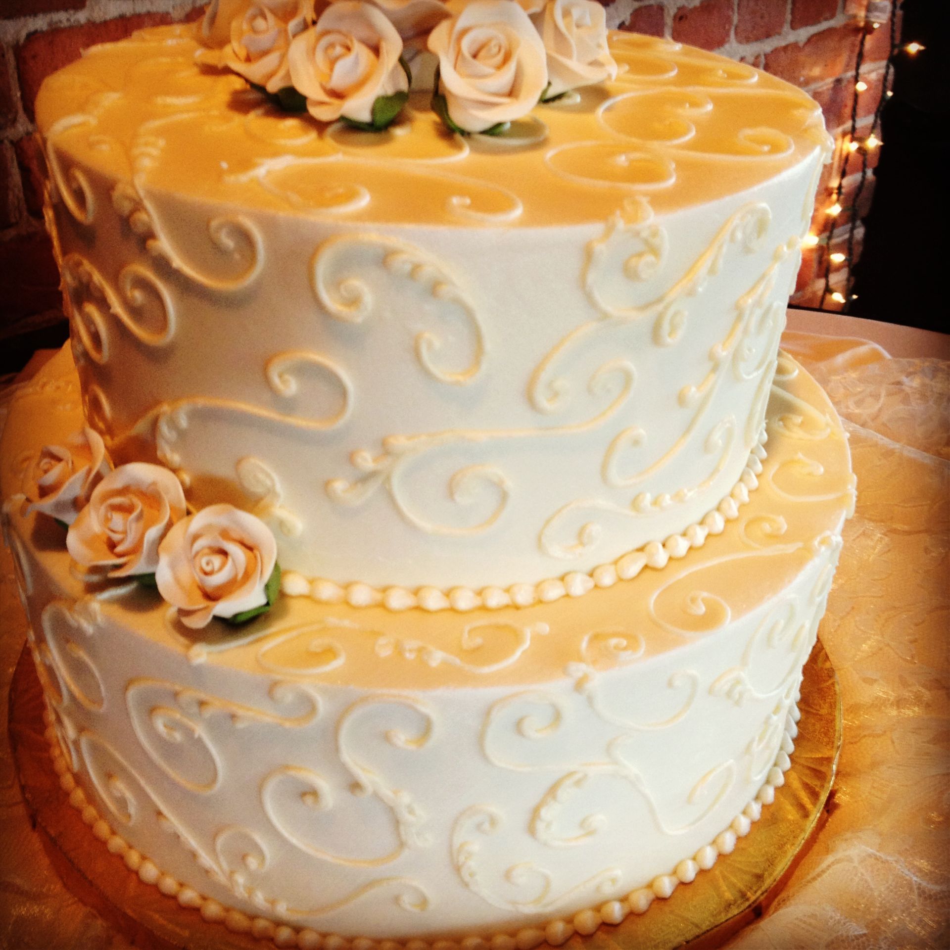 a wedding cake with white frosting and roses on top