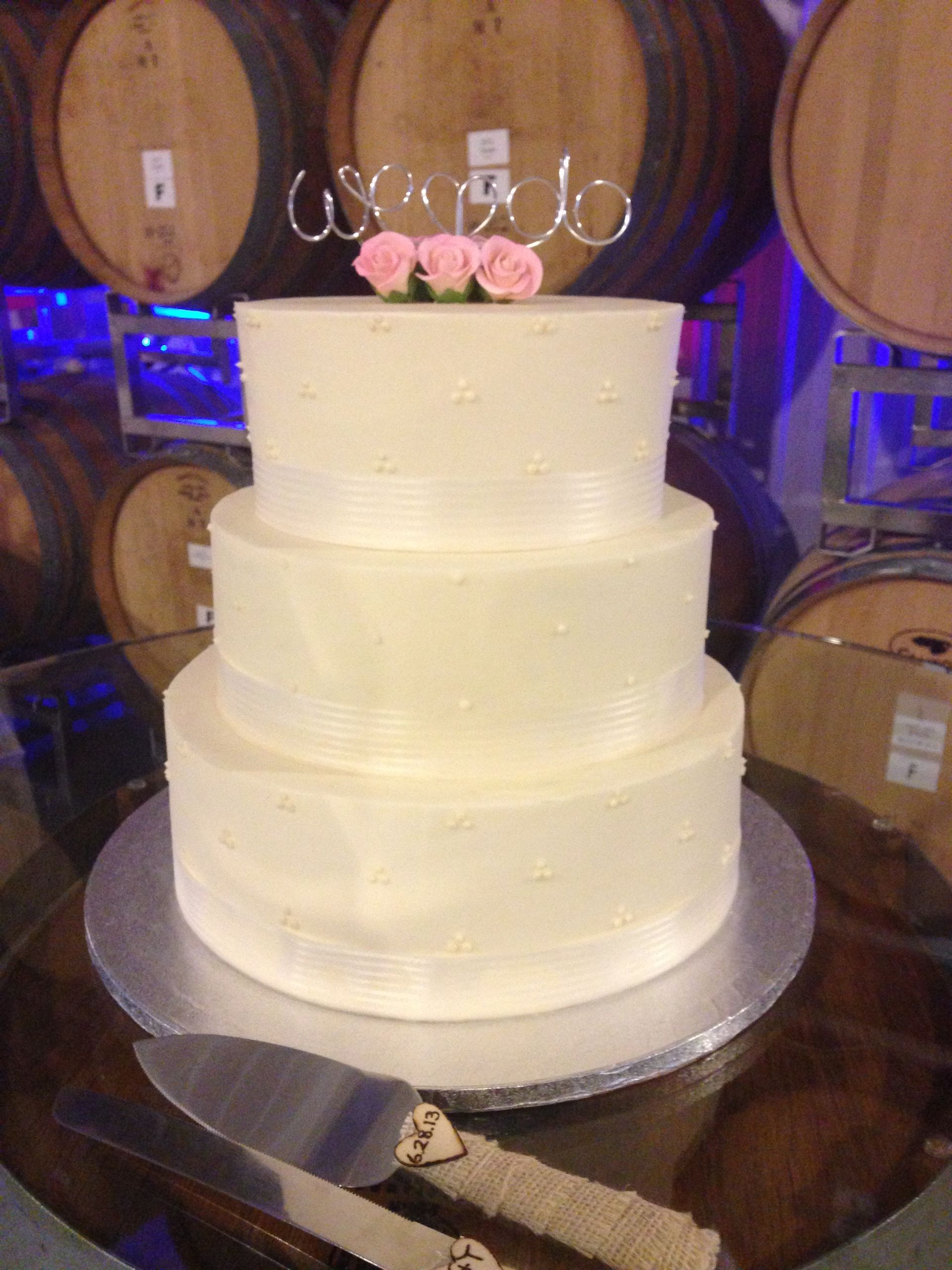 a wedding cake is sitting on a table in front of wine barrels