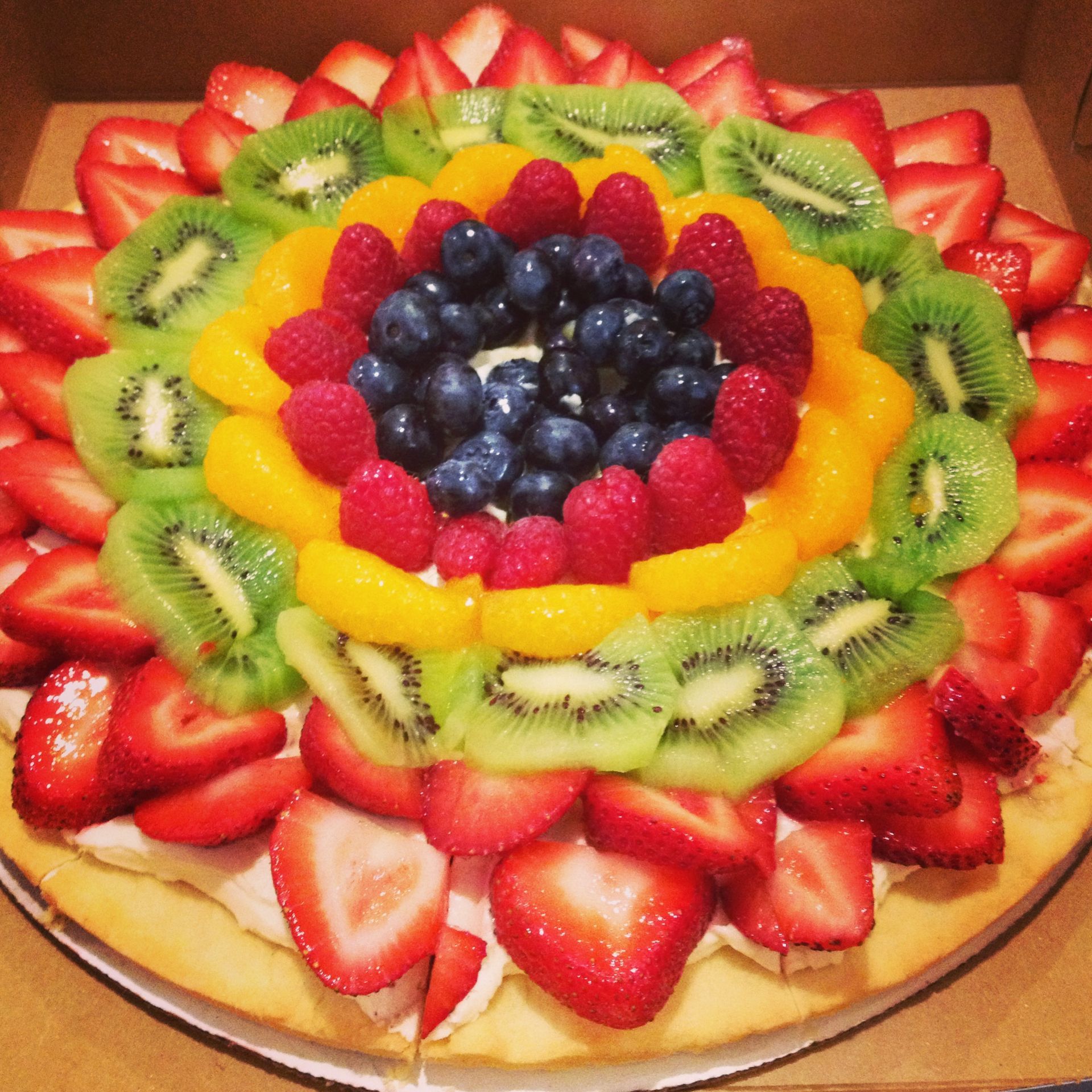 a pizza with strawberries kiwi and blueberries on top