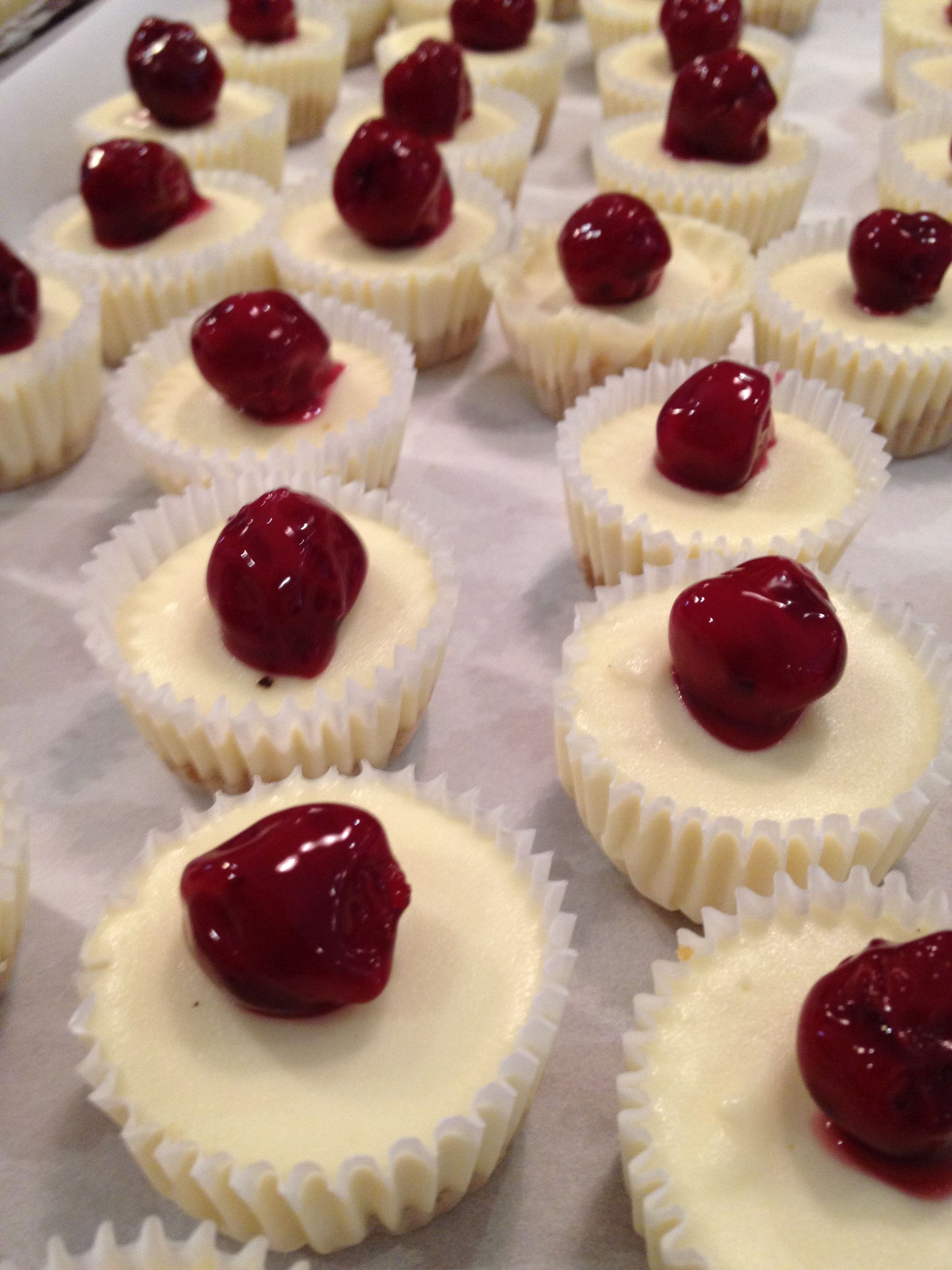 a bunch of cheesecake cupcakes with cherries on top