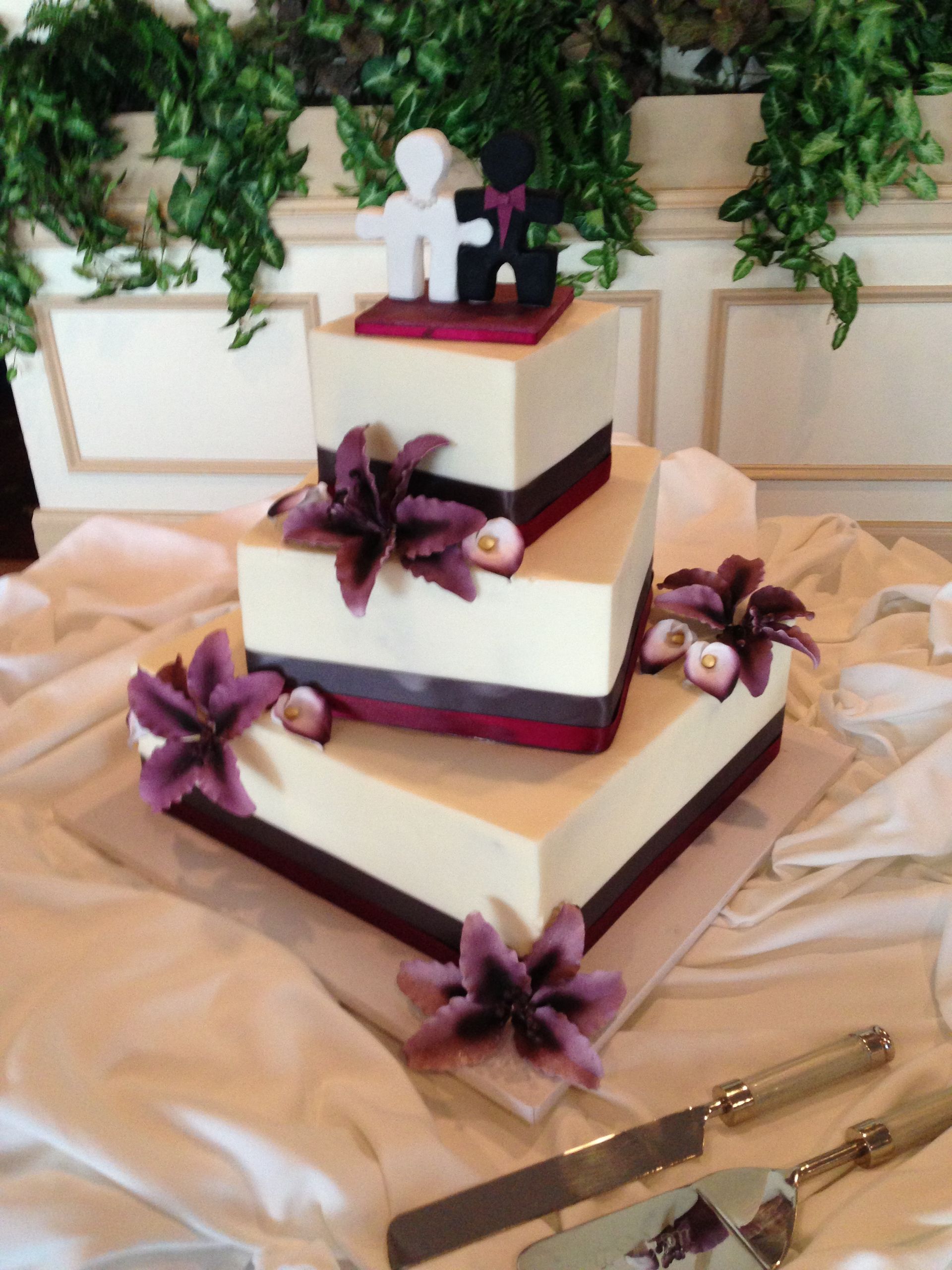 a wedding cake with purple flowers and a puzzle piece on top