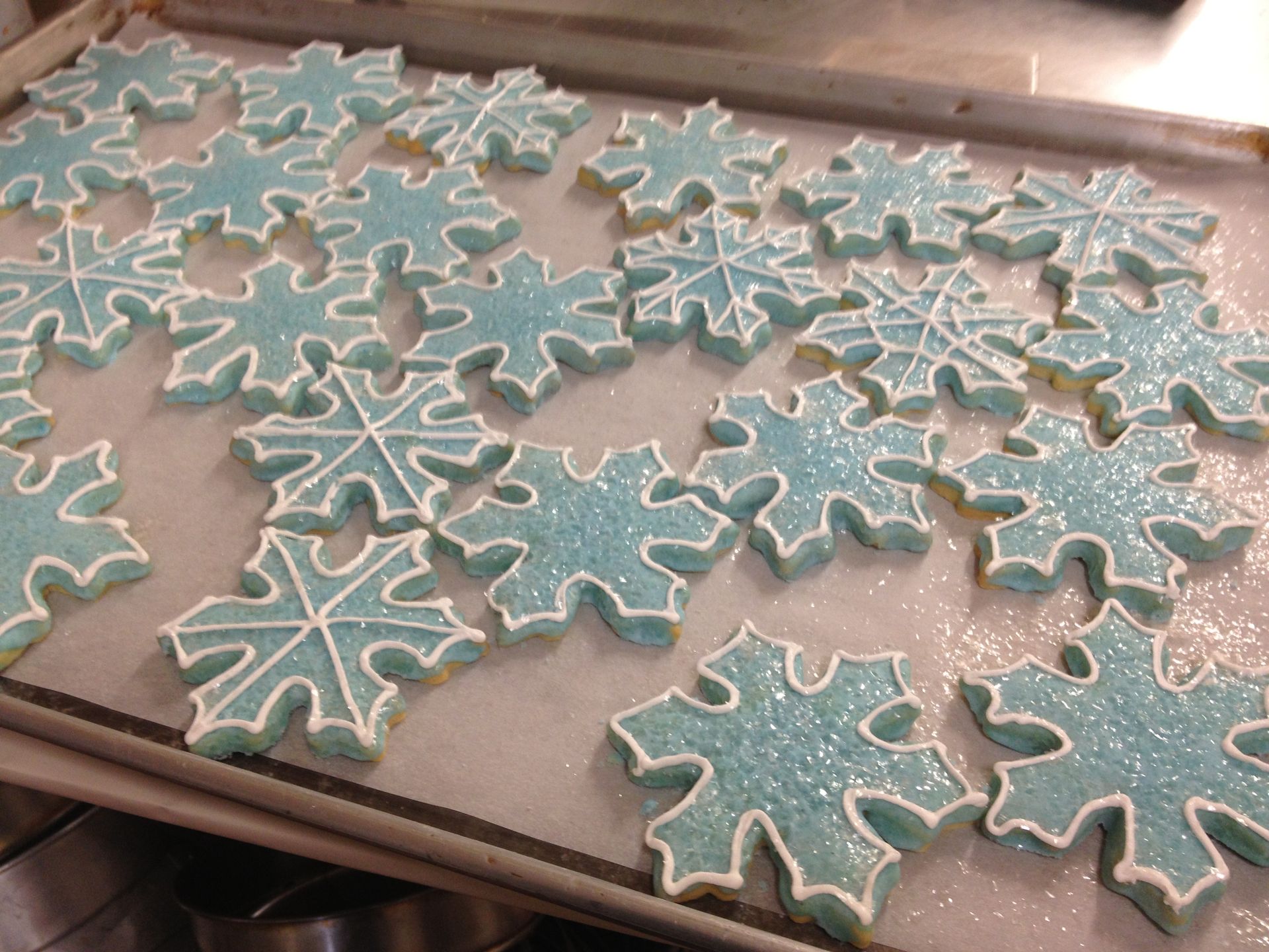 a tray of snowflake shaped cookies with blue frosting and sprinkles