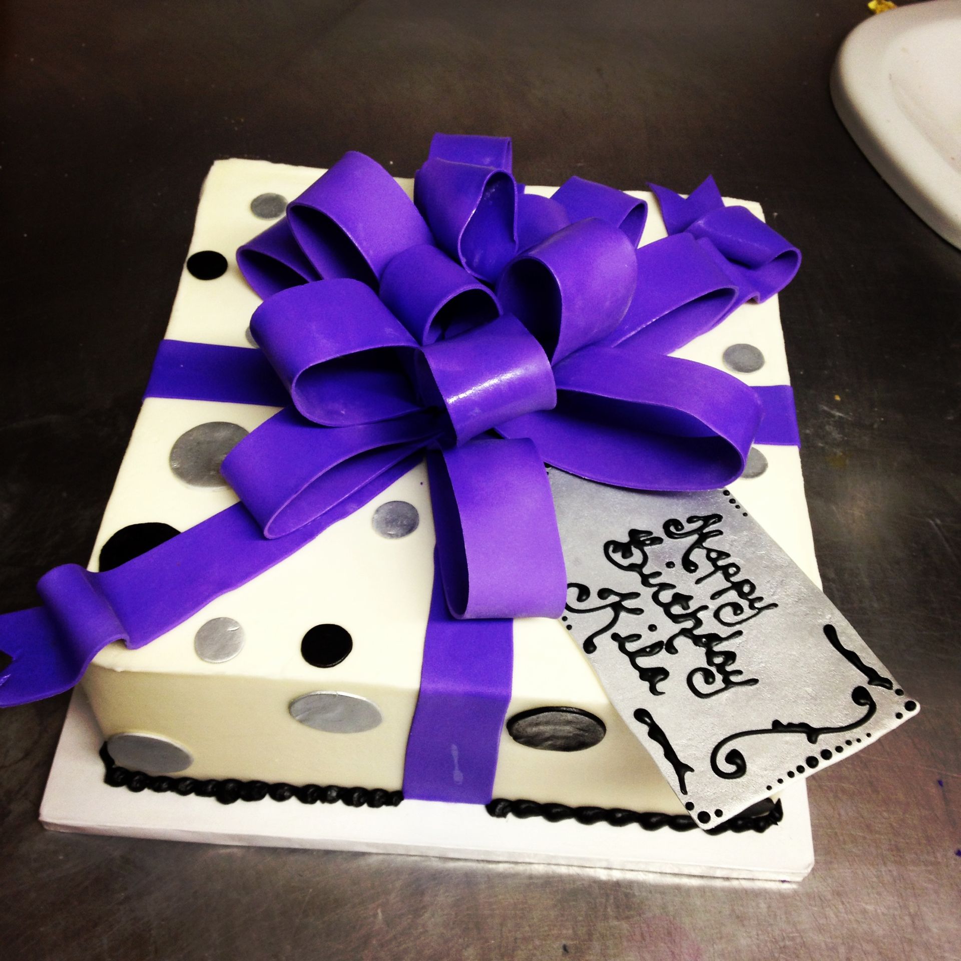 a birthday cake with a purple bow and tag that says happy birthday