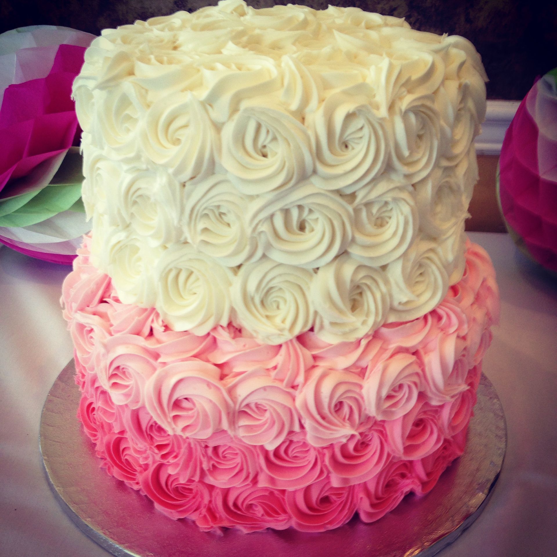 a pink and white cake with roses on it
