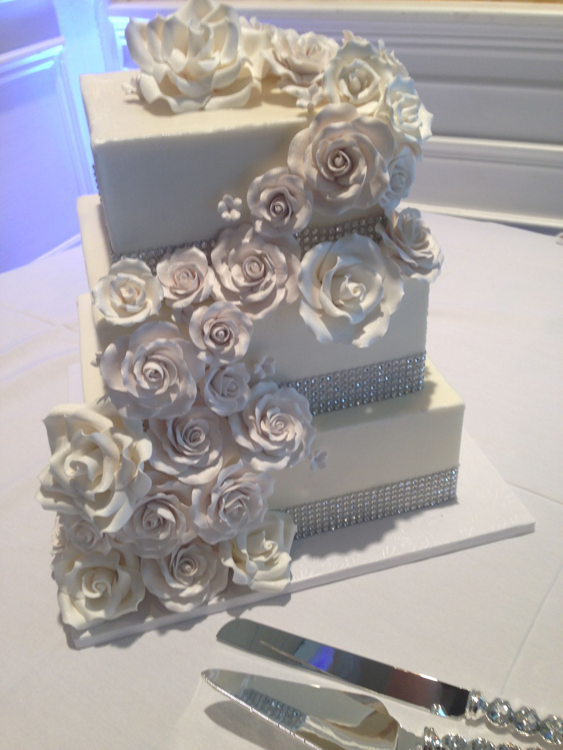a wedding cake with white roses and silver rhinestones