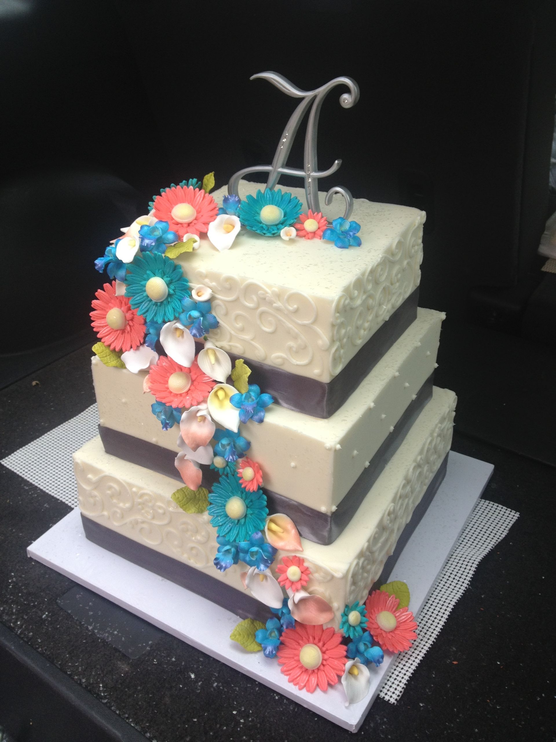 a wedding cake with flowers and a letter a on top