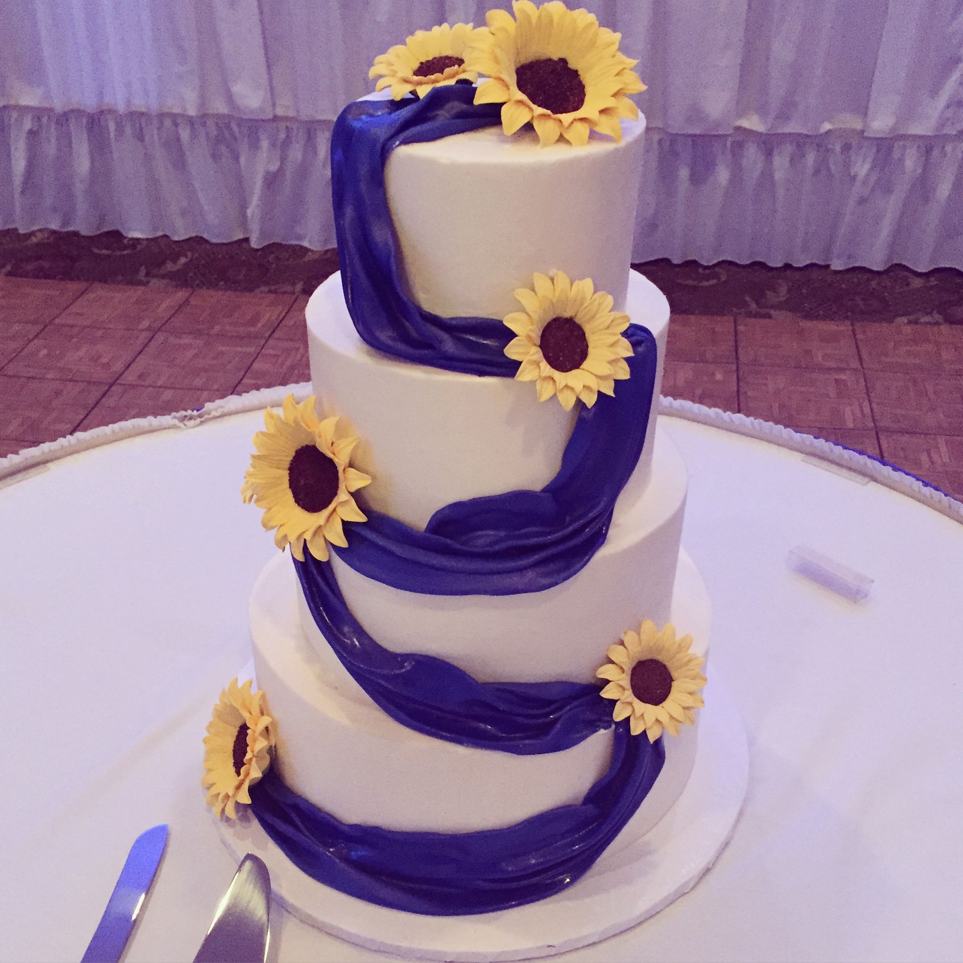 a wedding cake with blue and yellow sunflowers on it