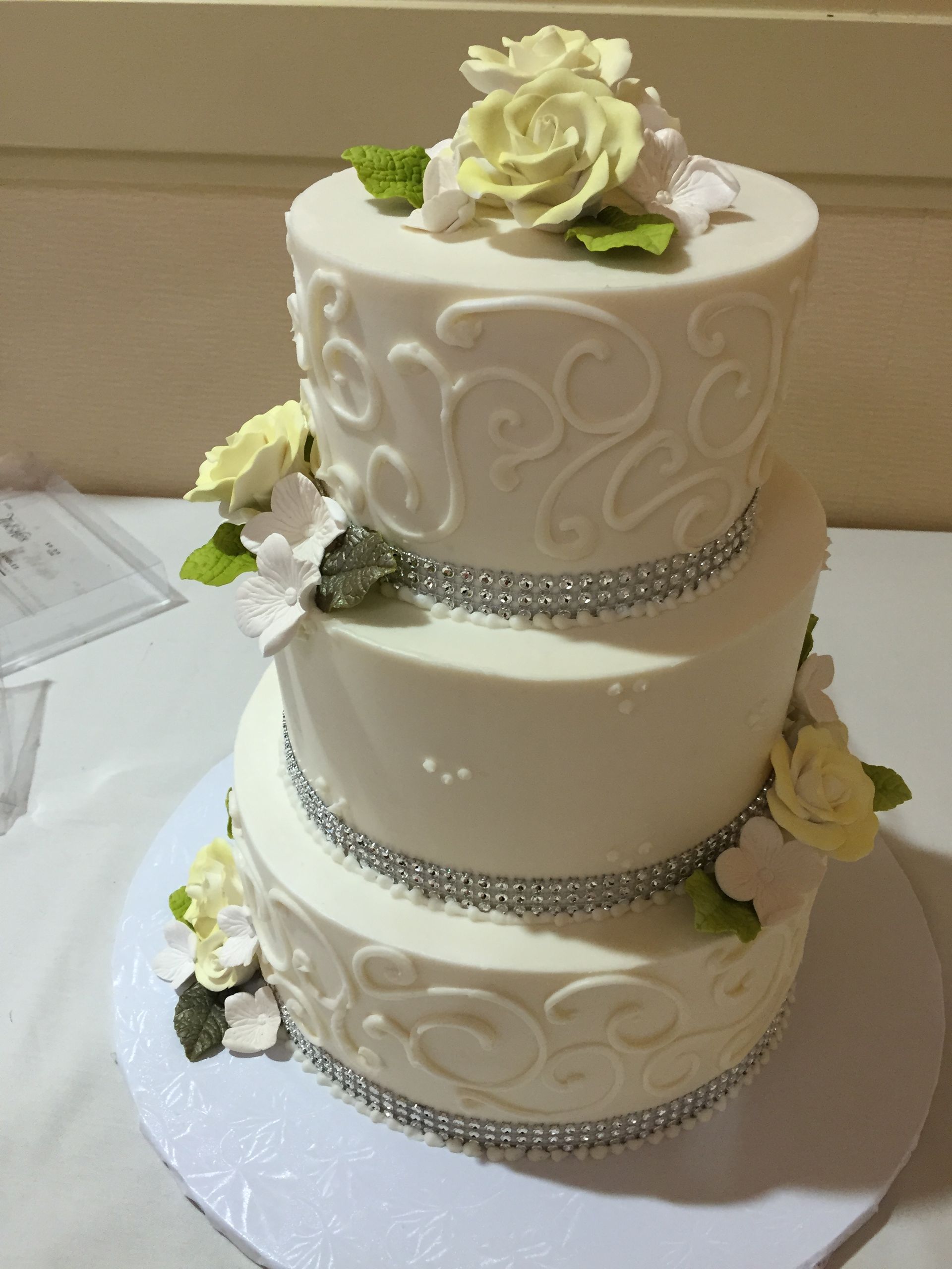 a white wedding cake with flowers and rhinestones on it