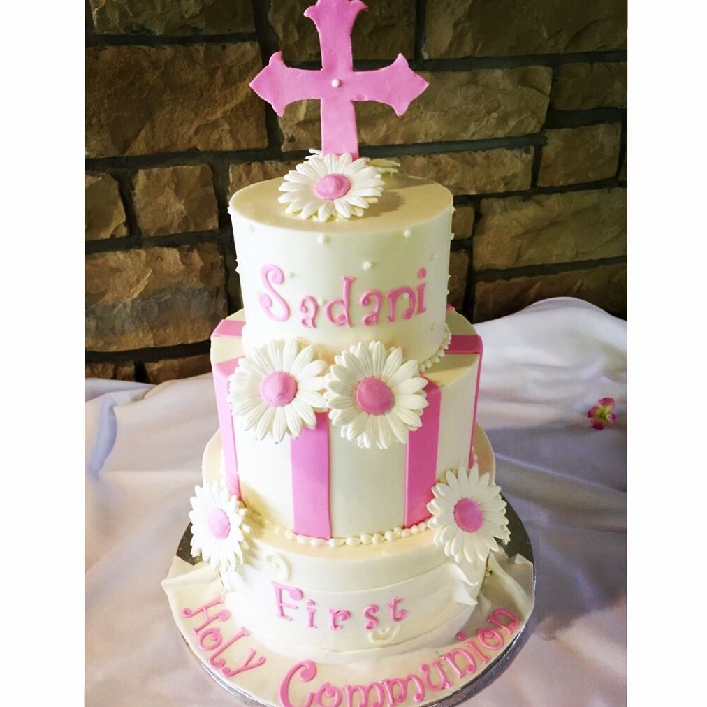 a first communion cake for a girl with a pink cross on top