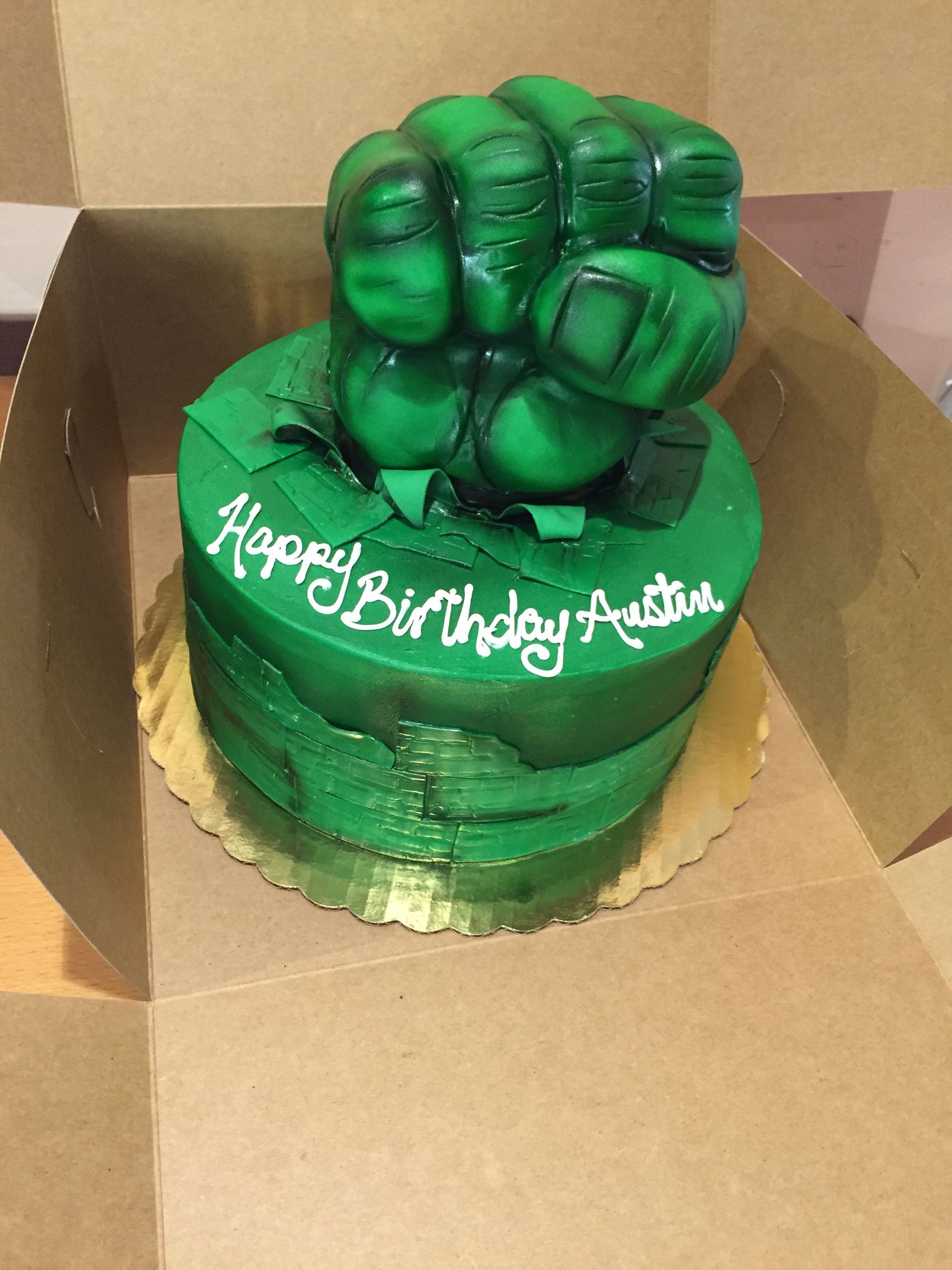 a birthday cake with a green hulk fist on top