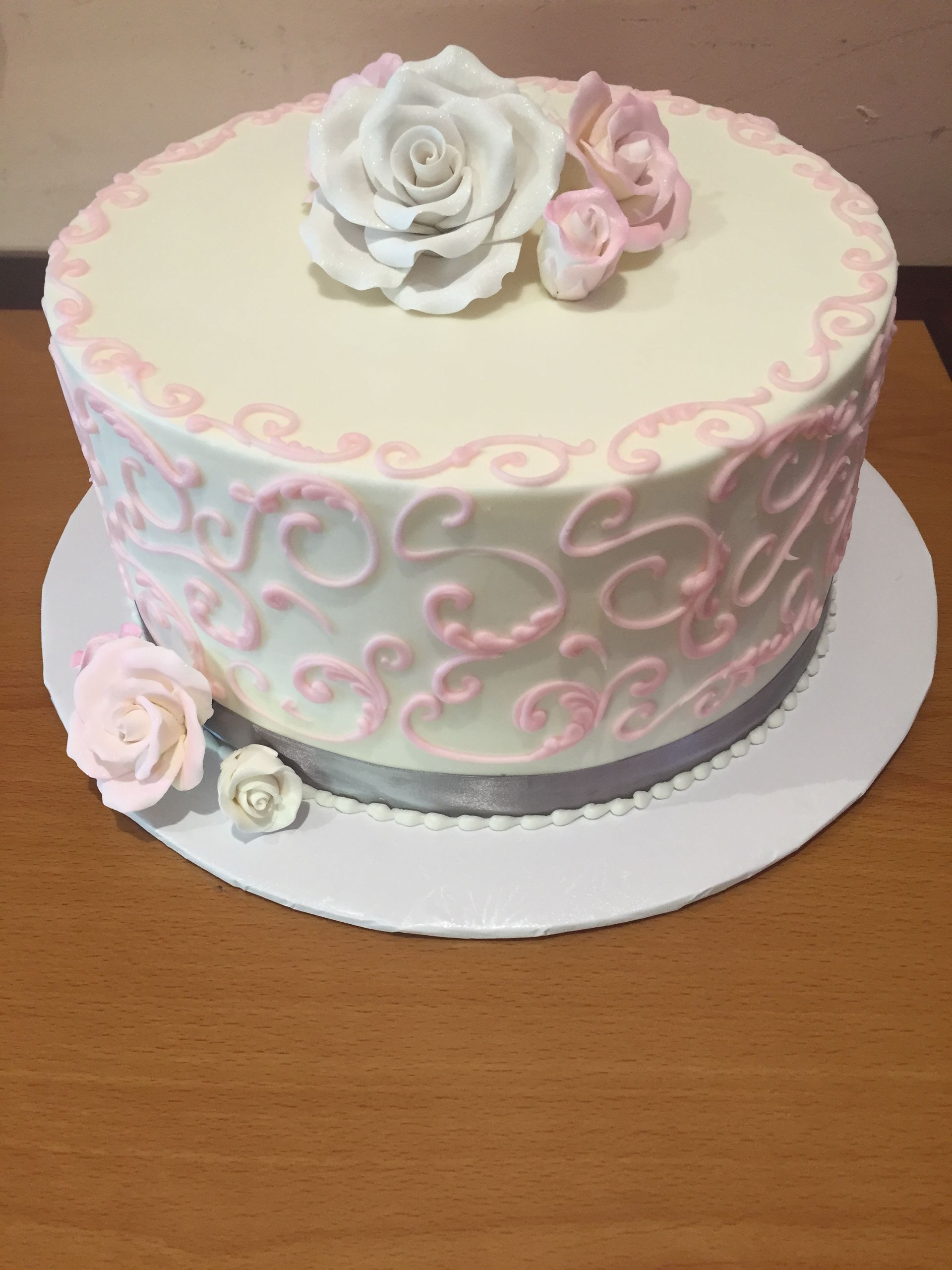 a white and pink cake with roses on top