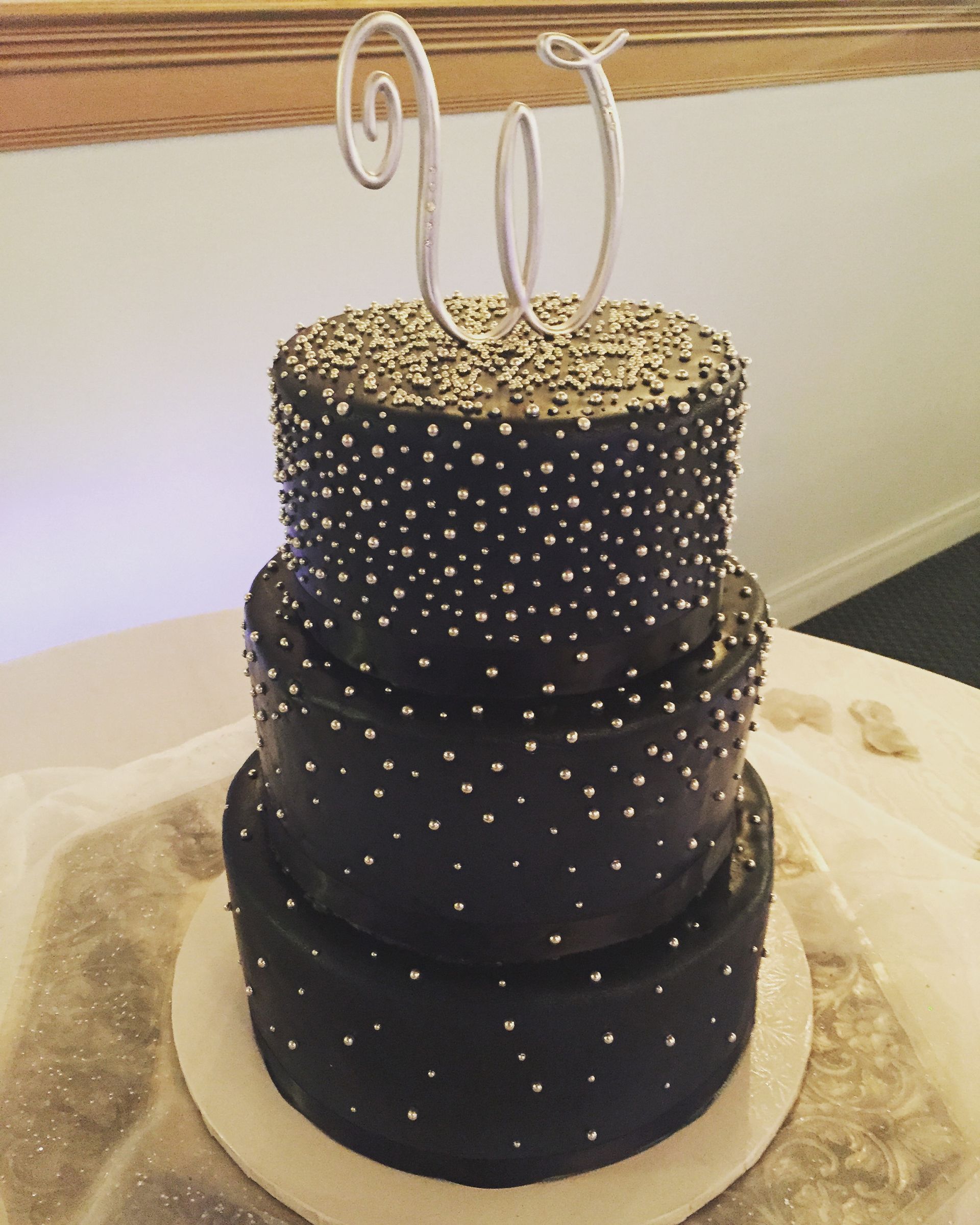 a black and gold cake with the letter w on top