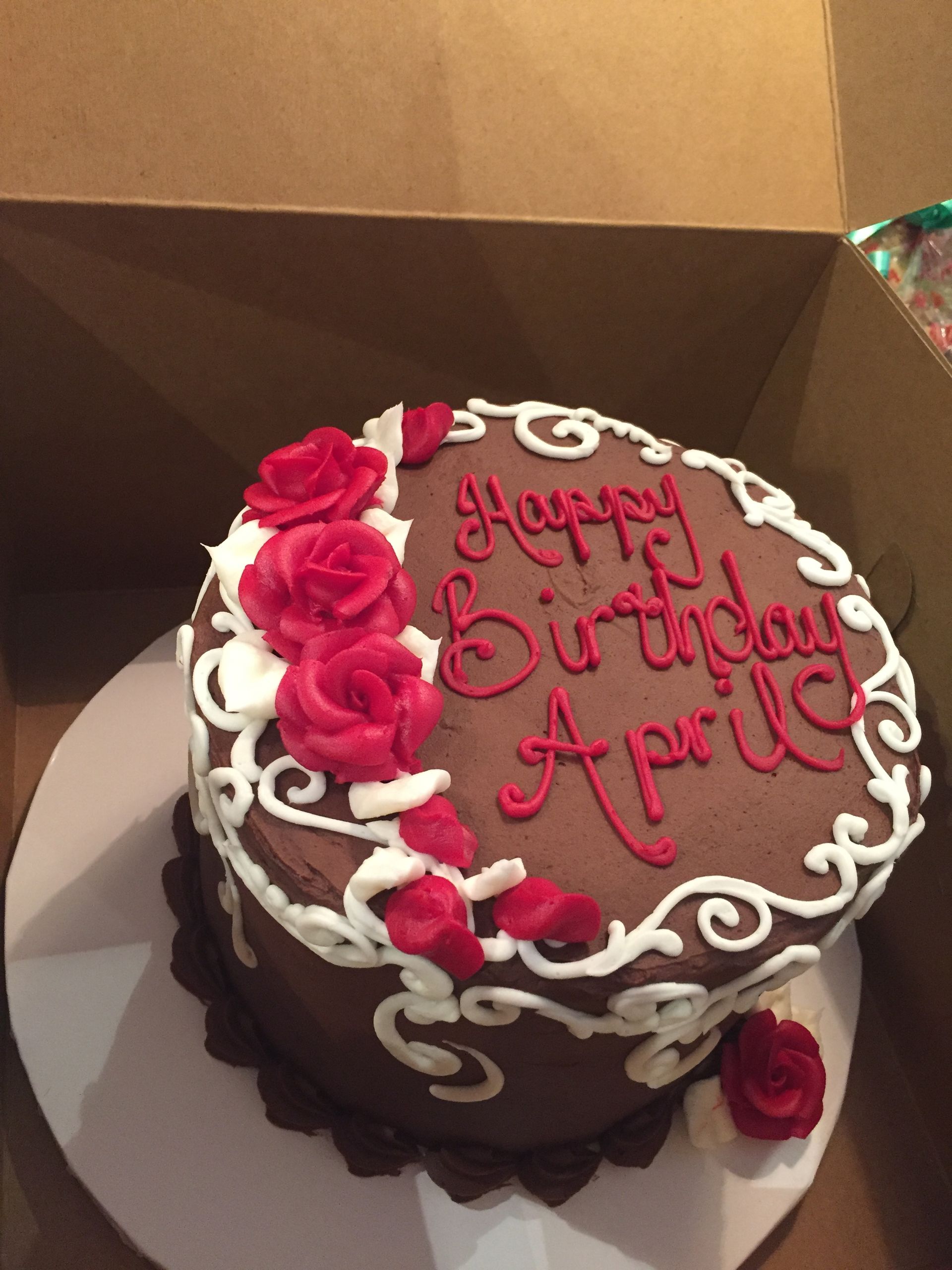 a birthday cake with red roses and white frosting says happy birthday april