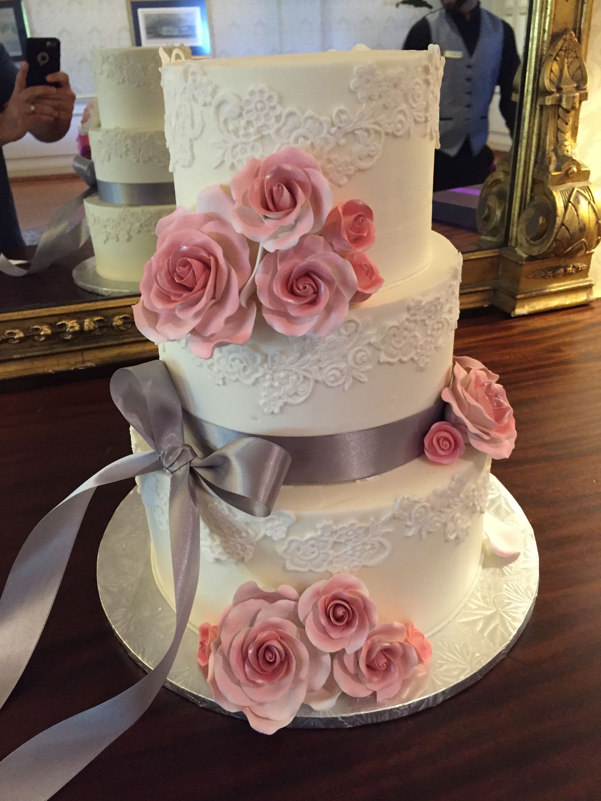 a wedding cake with pink roses and lace on it