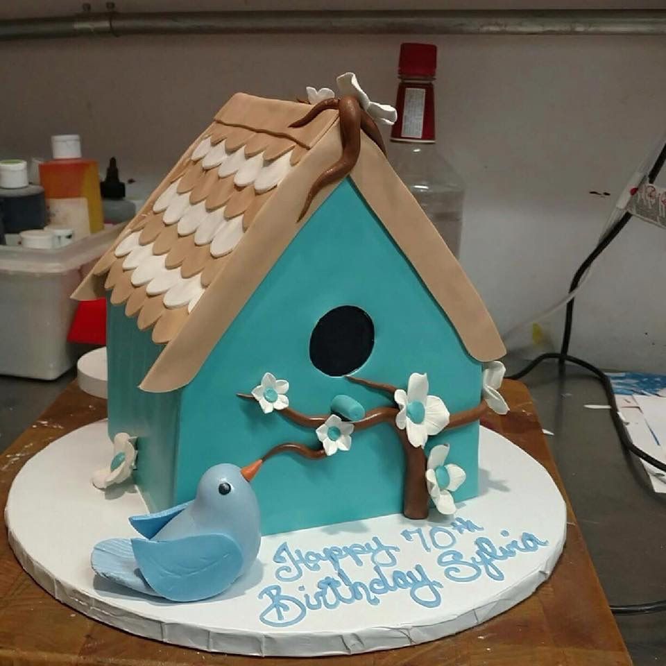 a cake that looks like a birdhouse with flowers and a bird on it