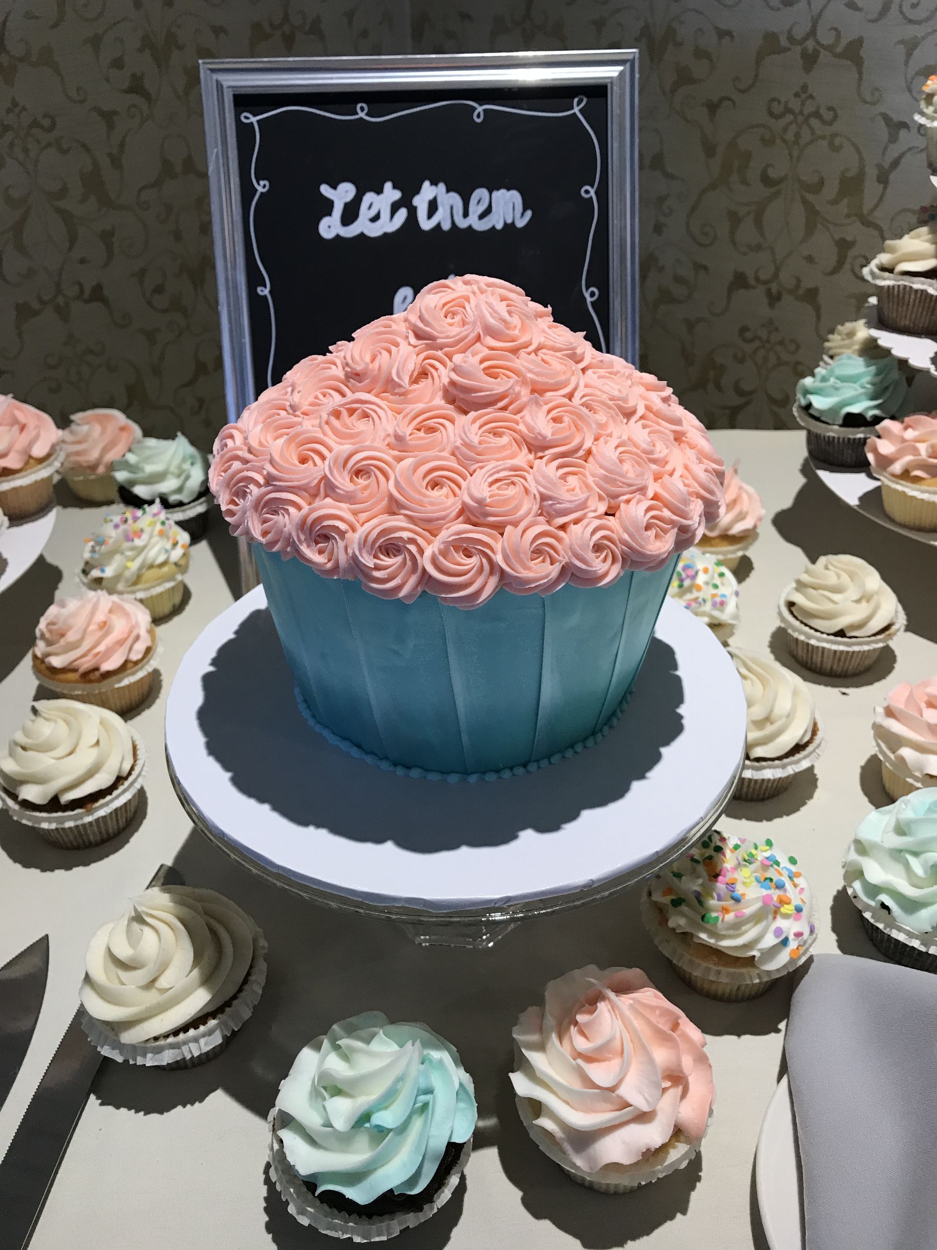 a table with cupcakes and a sign that says let them