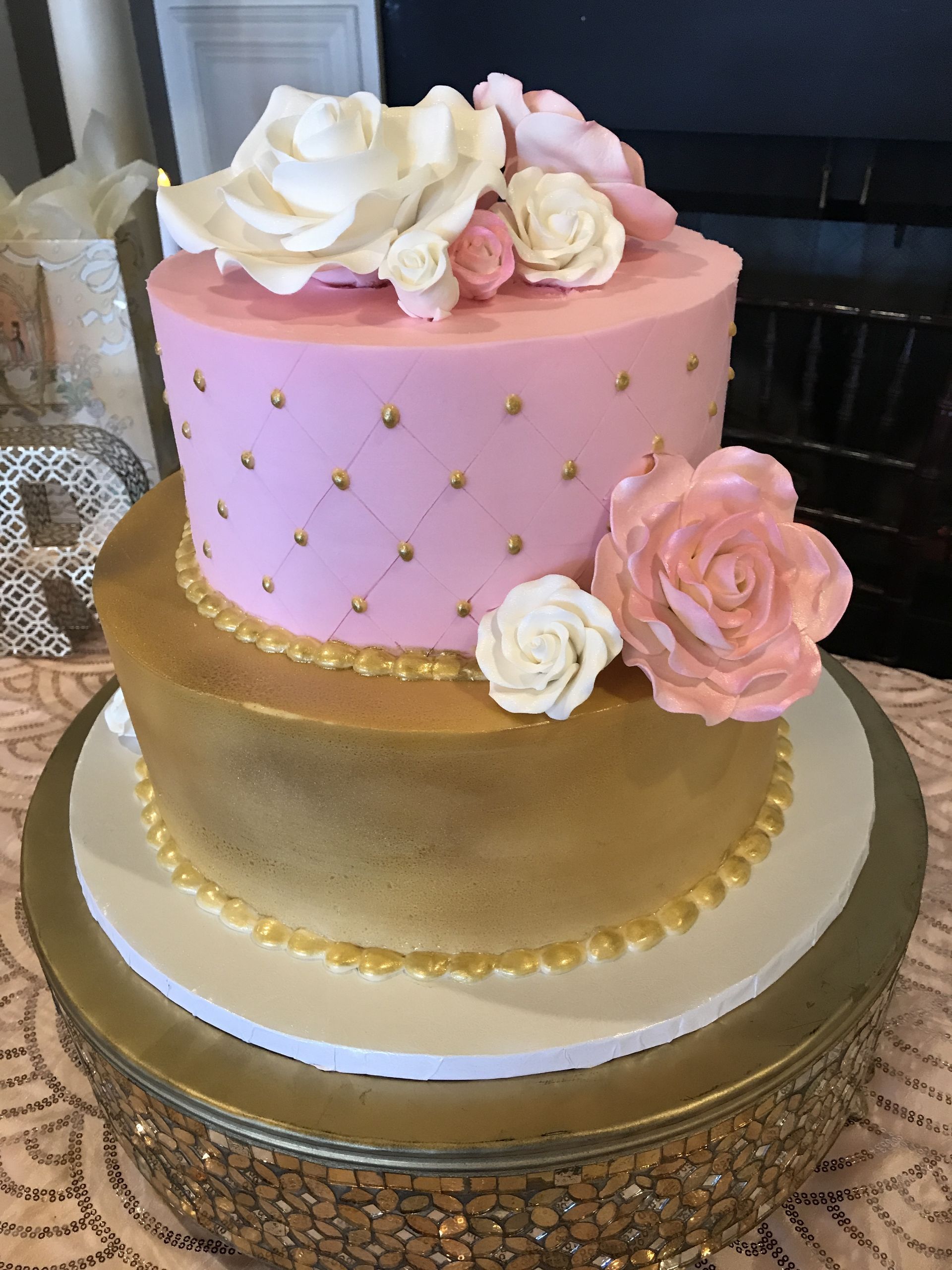a pink and gold cake with white roses on top