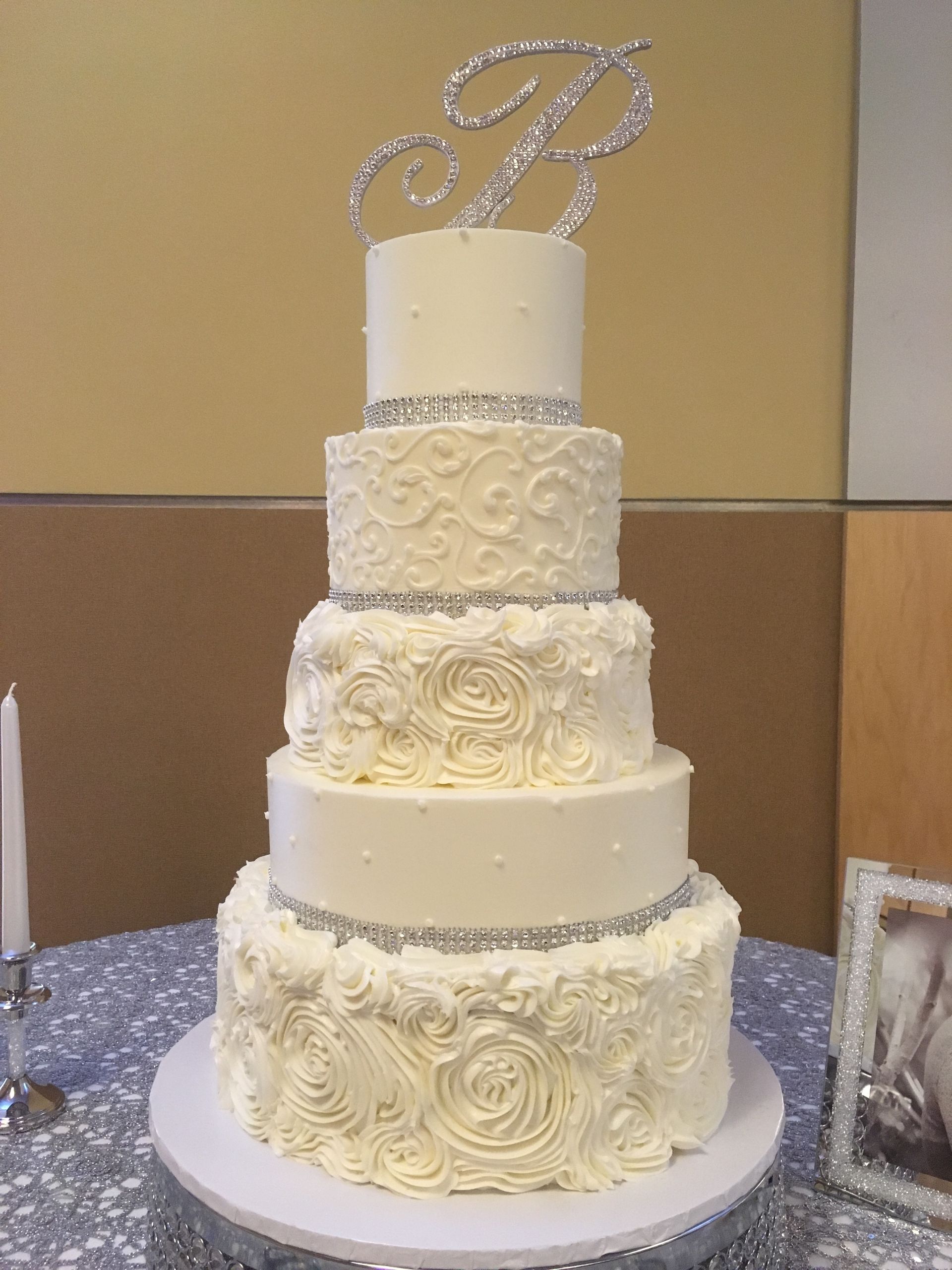 a white wedding cake with a monogram on top is sitting on a table .
