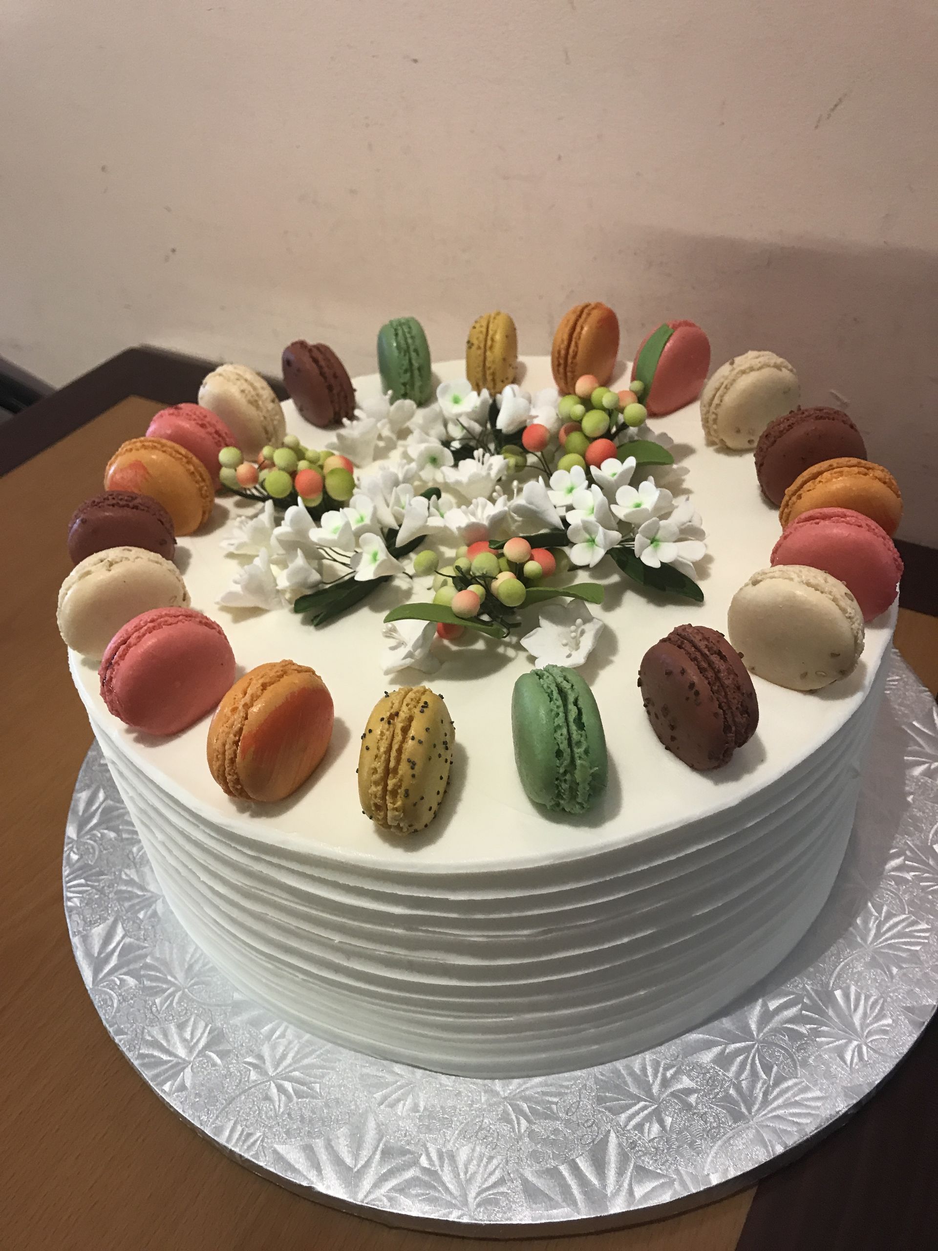 a white cake with macarons and flowers on top