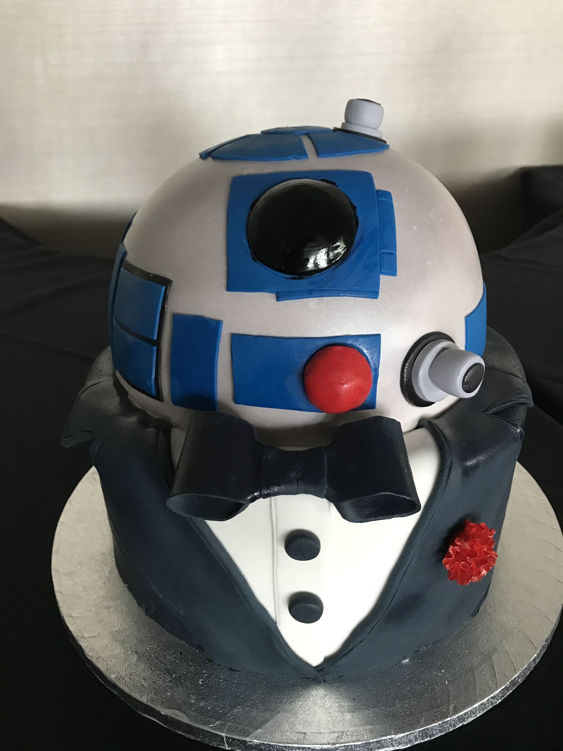 a cake that looks like a r2d2 wearing a tuxedo