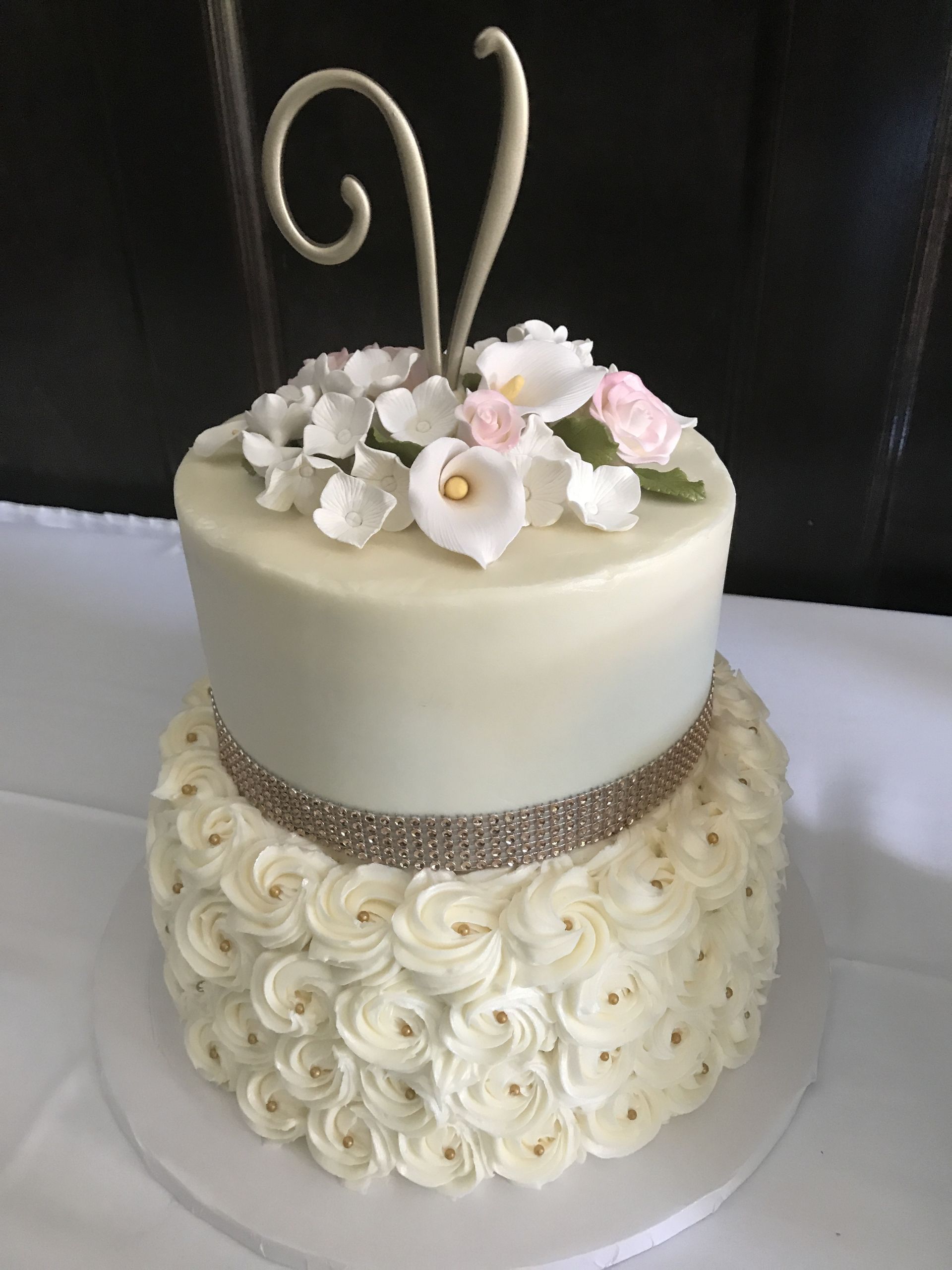a white cake with flowers and a letter v on top