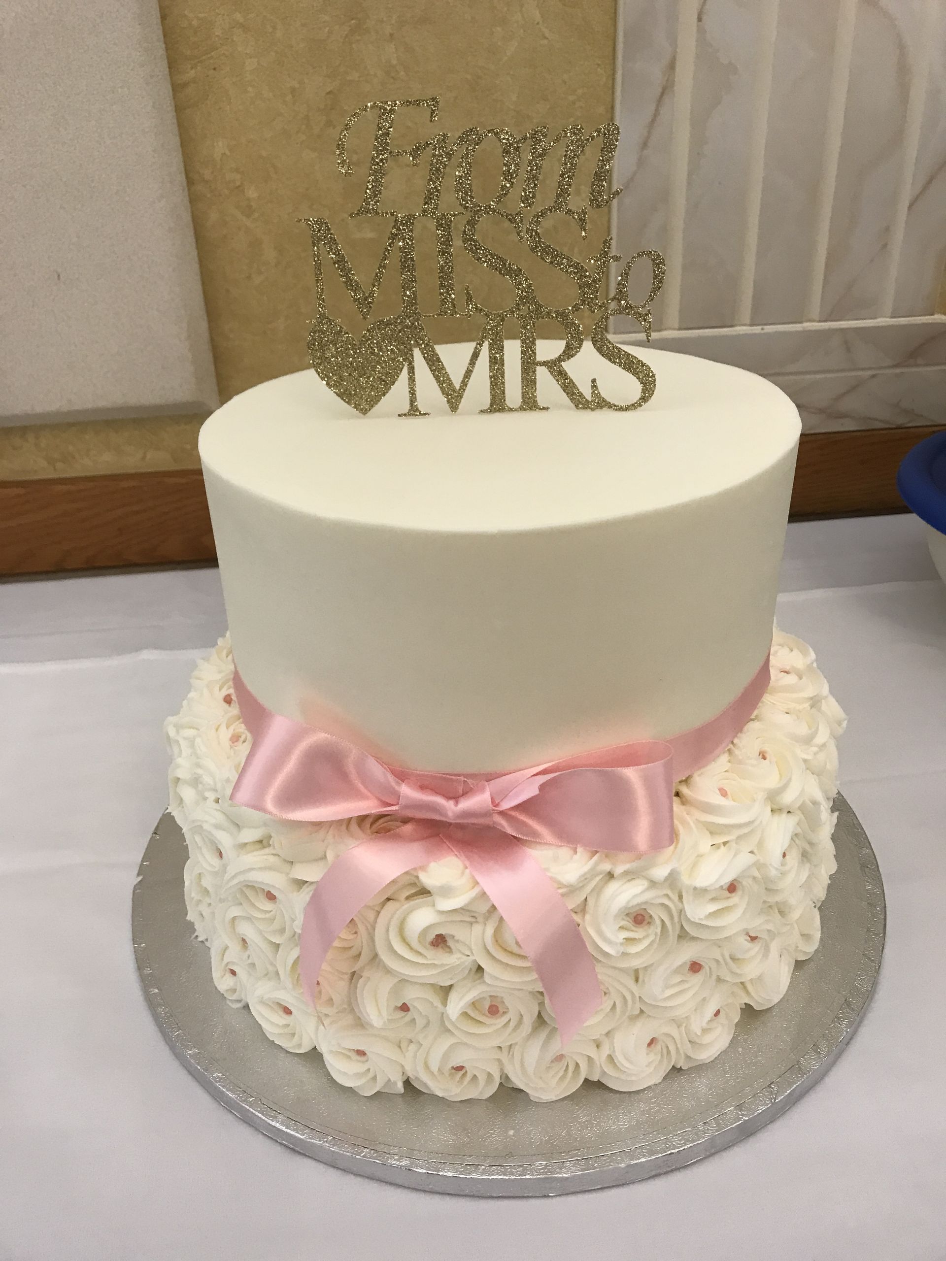 a white cake with a pink bow and a topper that says mrs. and mr.