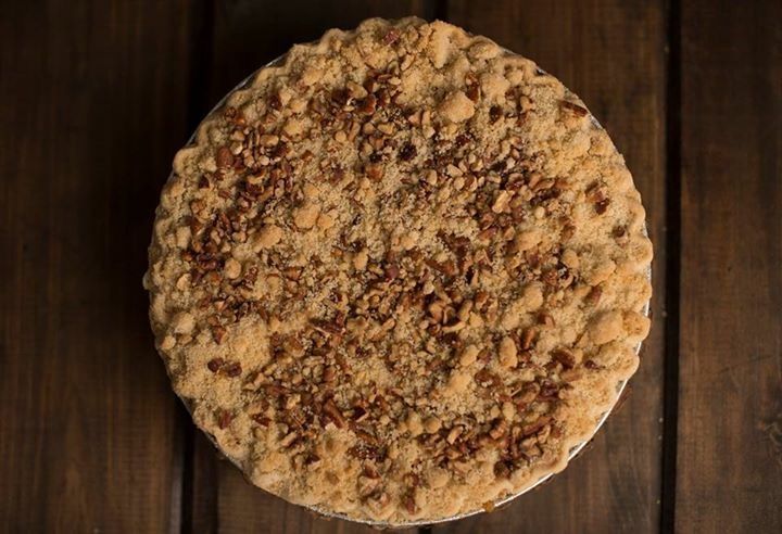 a pie with nuts on top is sitting on a wooden table .