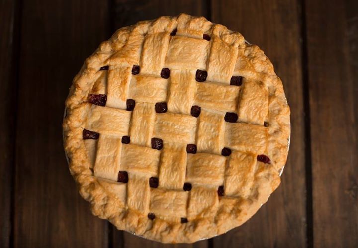 a pie with a lattice crust is sitting on a wooden table .
